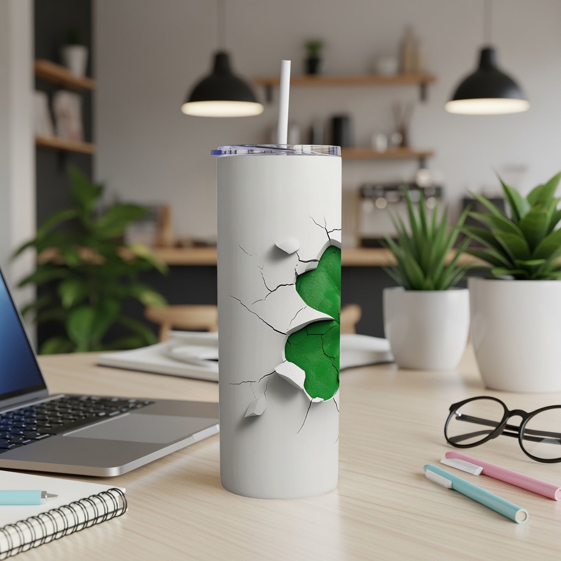 White tumbler with cracked green pattern, straw, on desk with laptop.