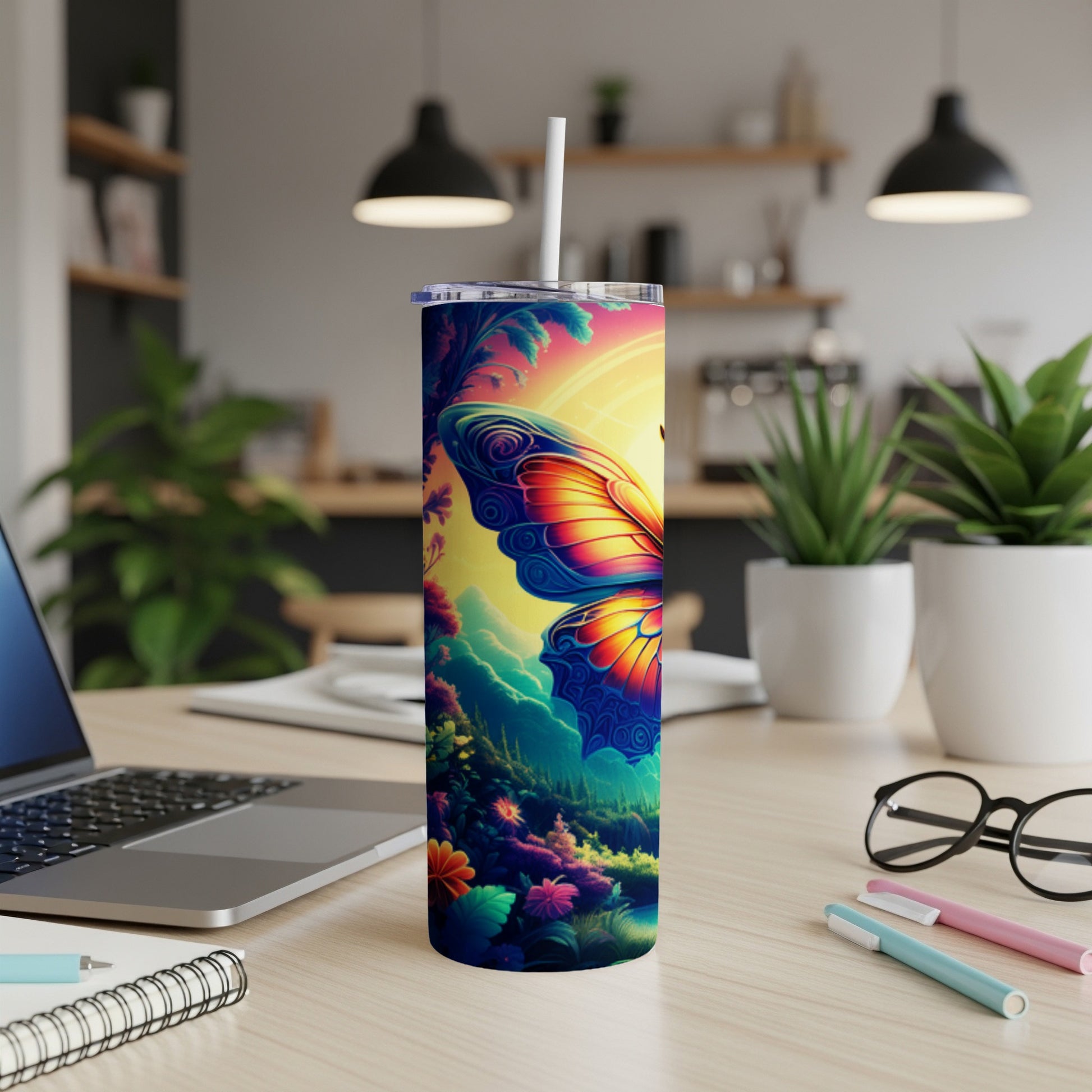 Tumbler with colorful butterfly design on a desk with laptop and pens.