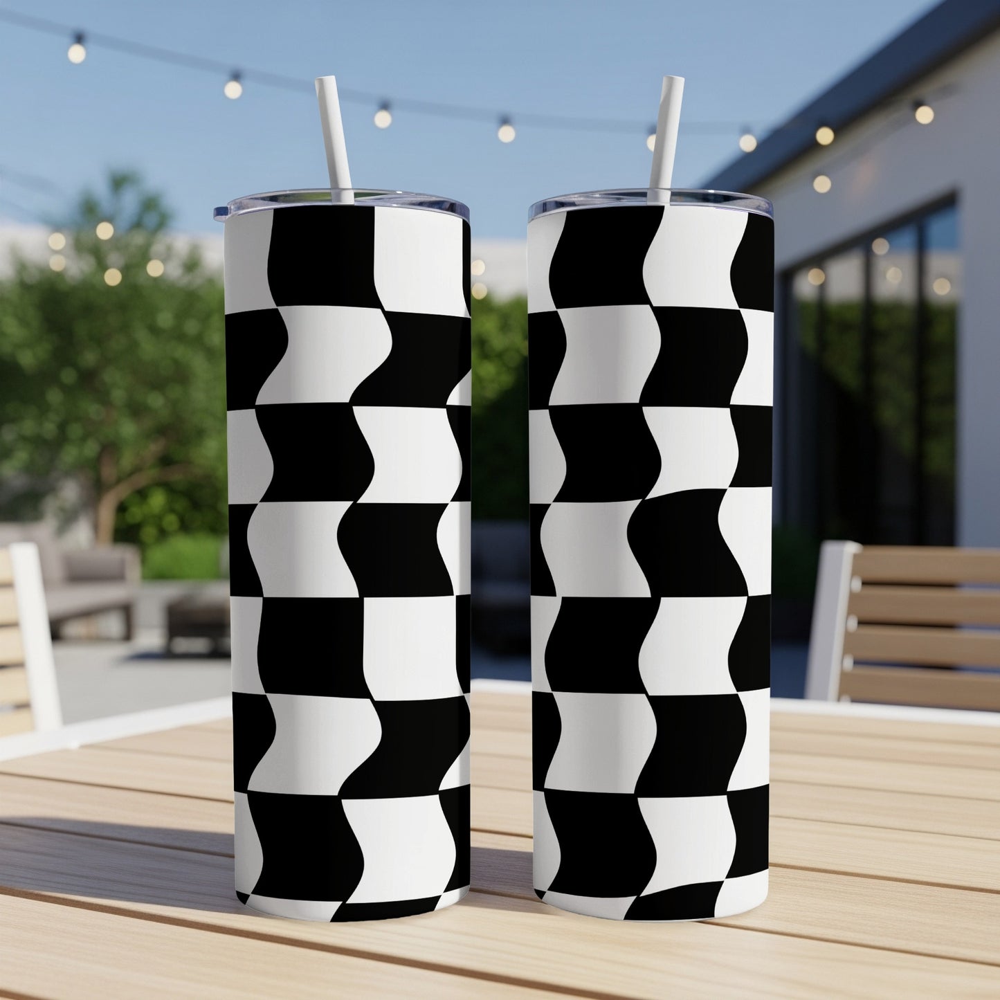 Two tall tumblers with a black and white checkerboard pattern sit on a wooden table.