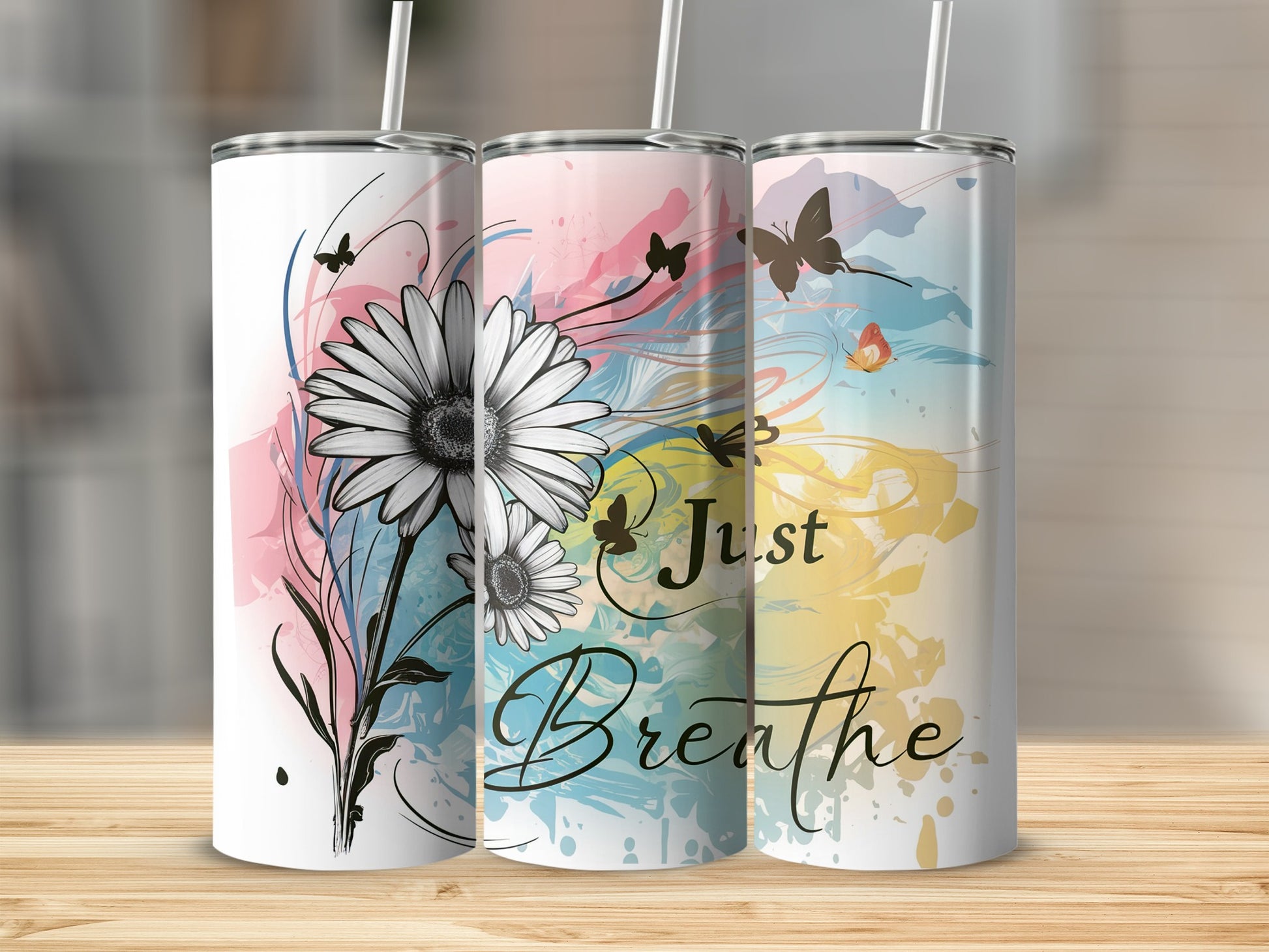 Three tumblers with floral and watercolor designs, one saying "Just Breathe."