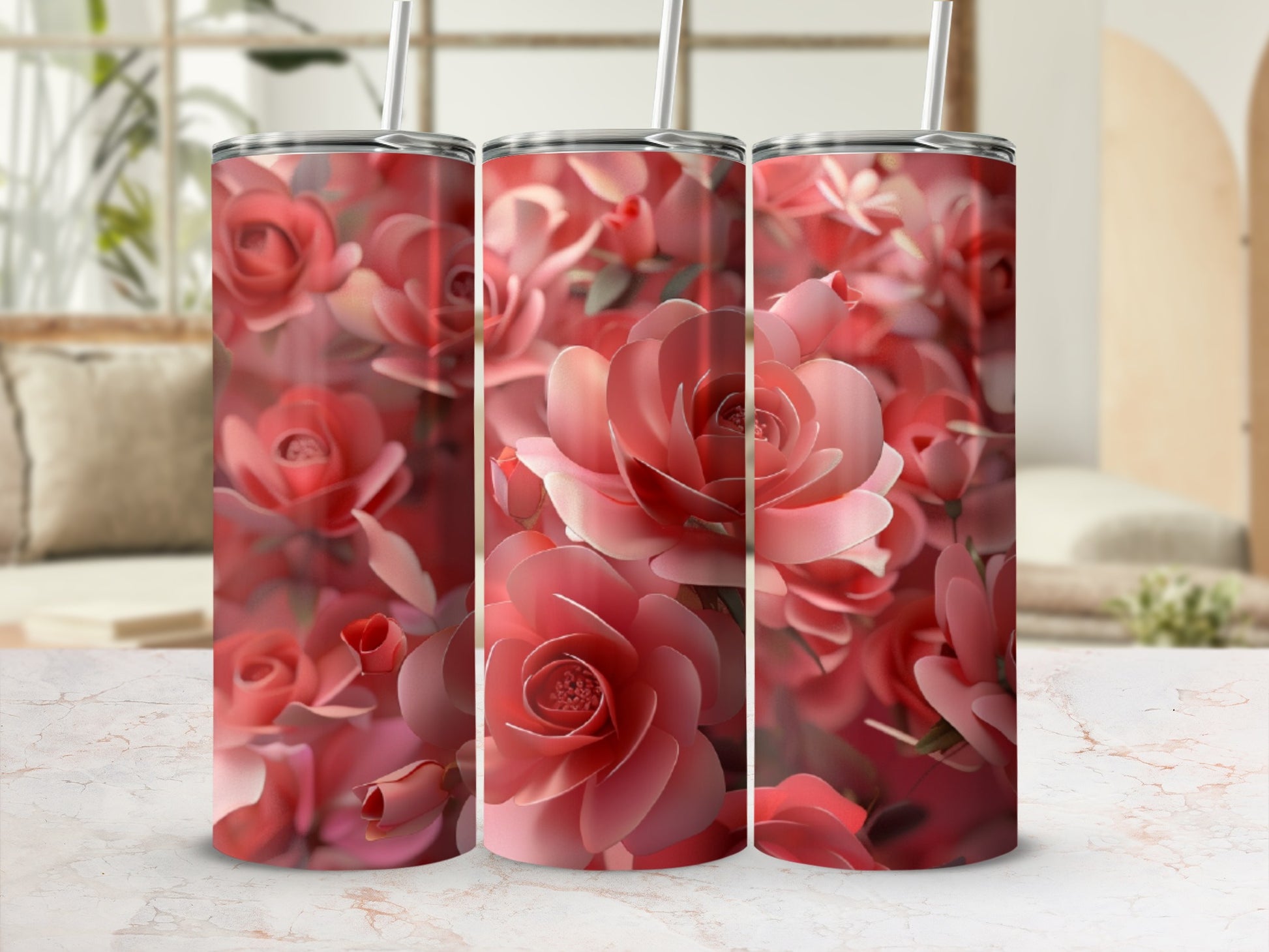 Three pink rose-patterned tumblers with straws against a blurred background.