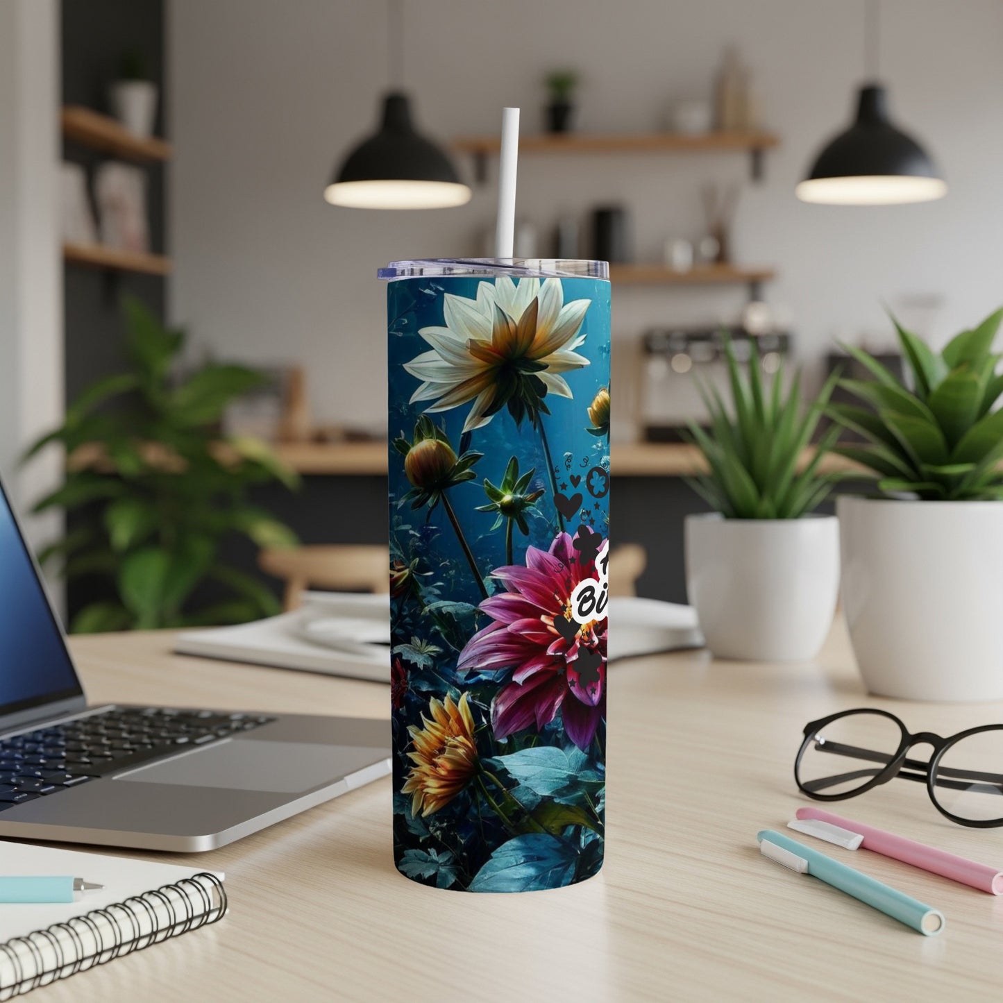 Dahlia flowers with bold "Bloom" text on a dark, floral-patterned tumbler.