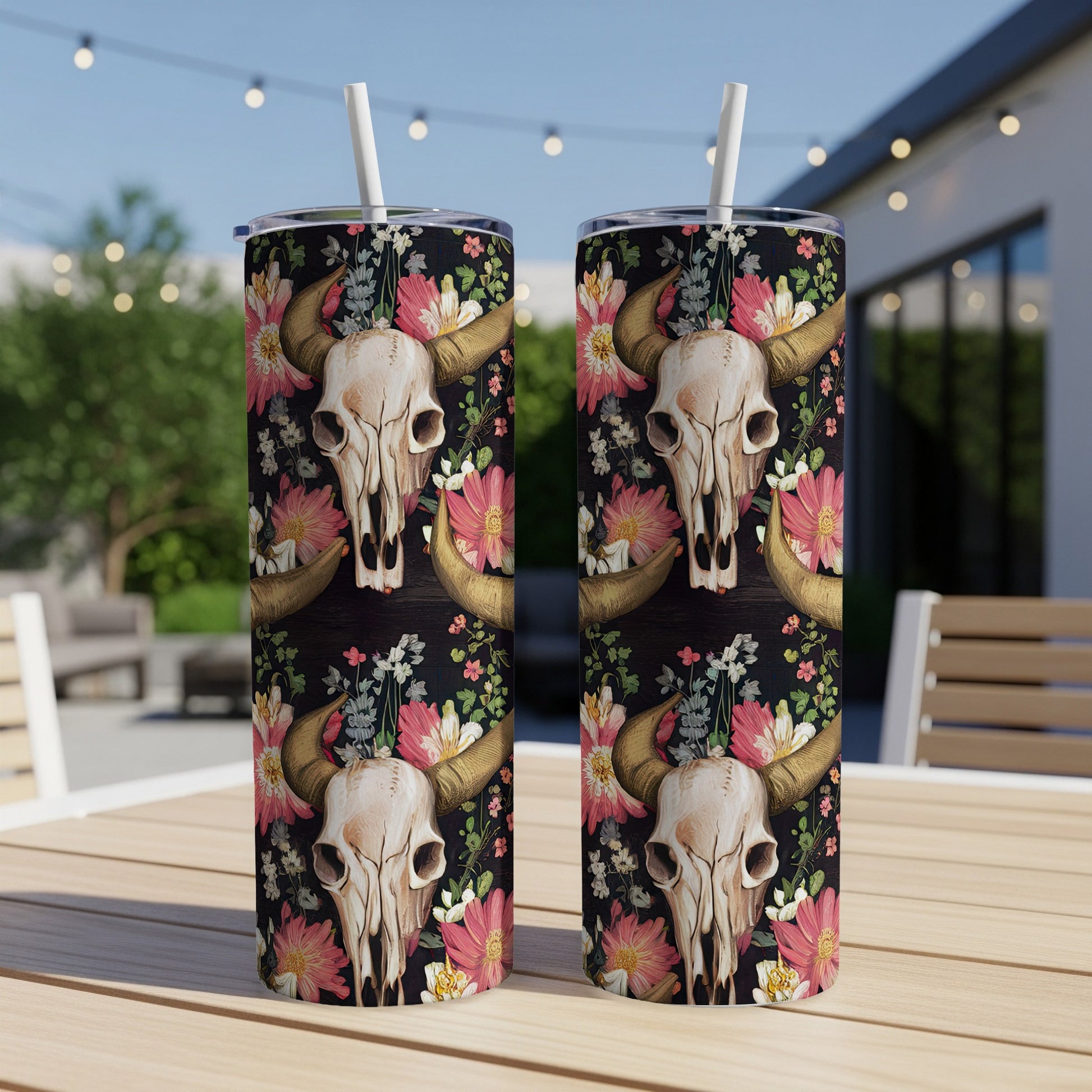 Two tumblers with steer skull and floral pattern on a table.
