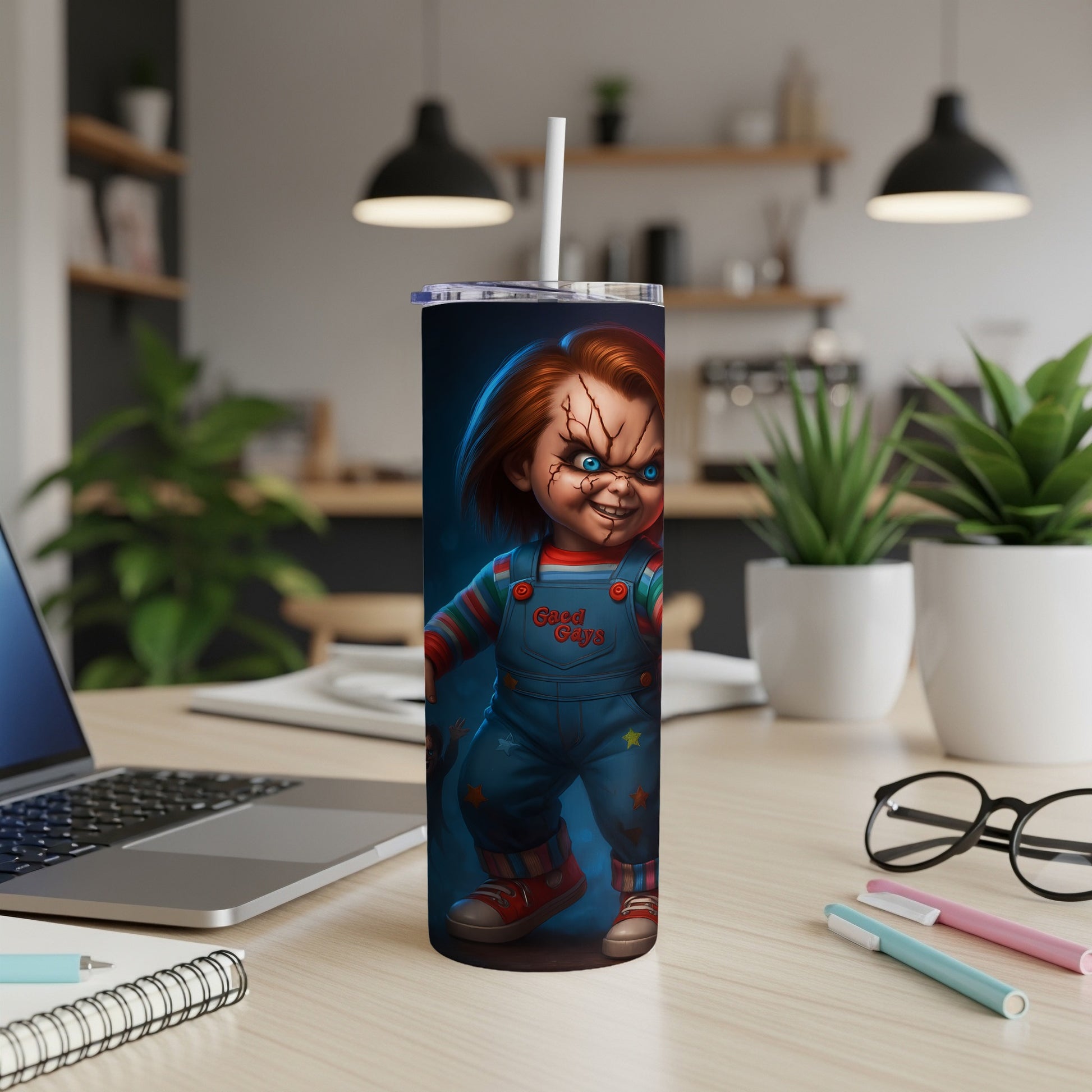 Tall tumbler with a Chucky doll design and a straw, on a desk.