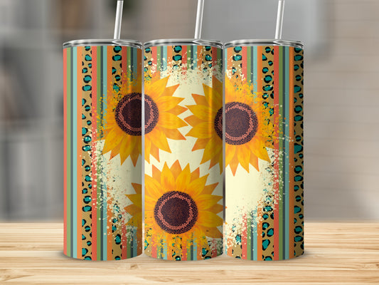 Three sunflowers on a striped and speckled tumbler with straws.