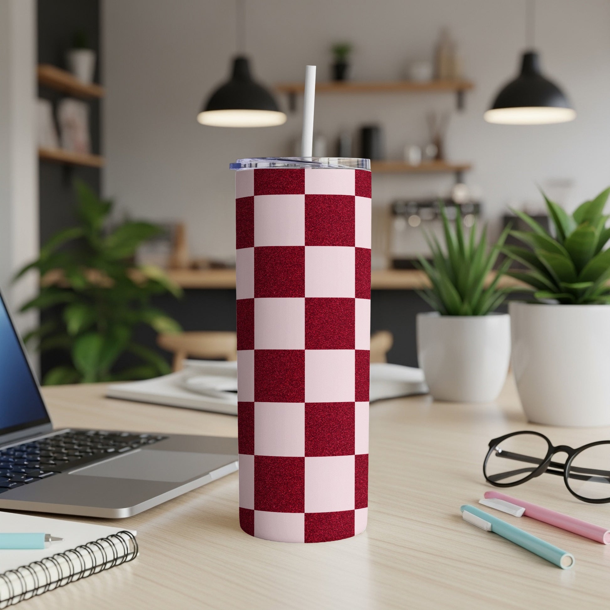 Red and pink checkered tumbler with a straw on a desk.