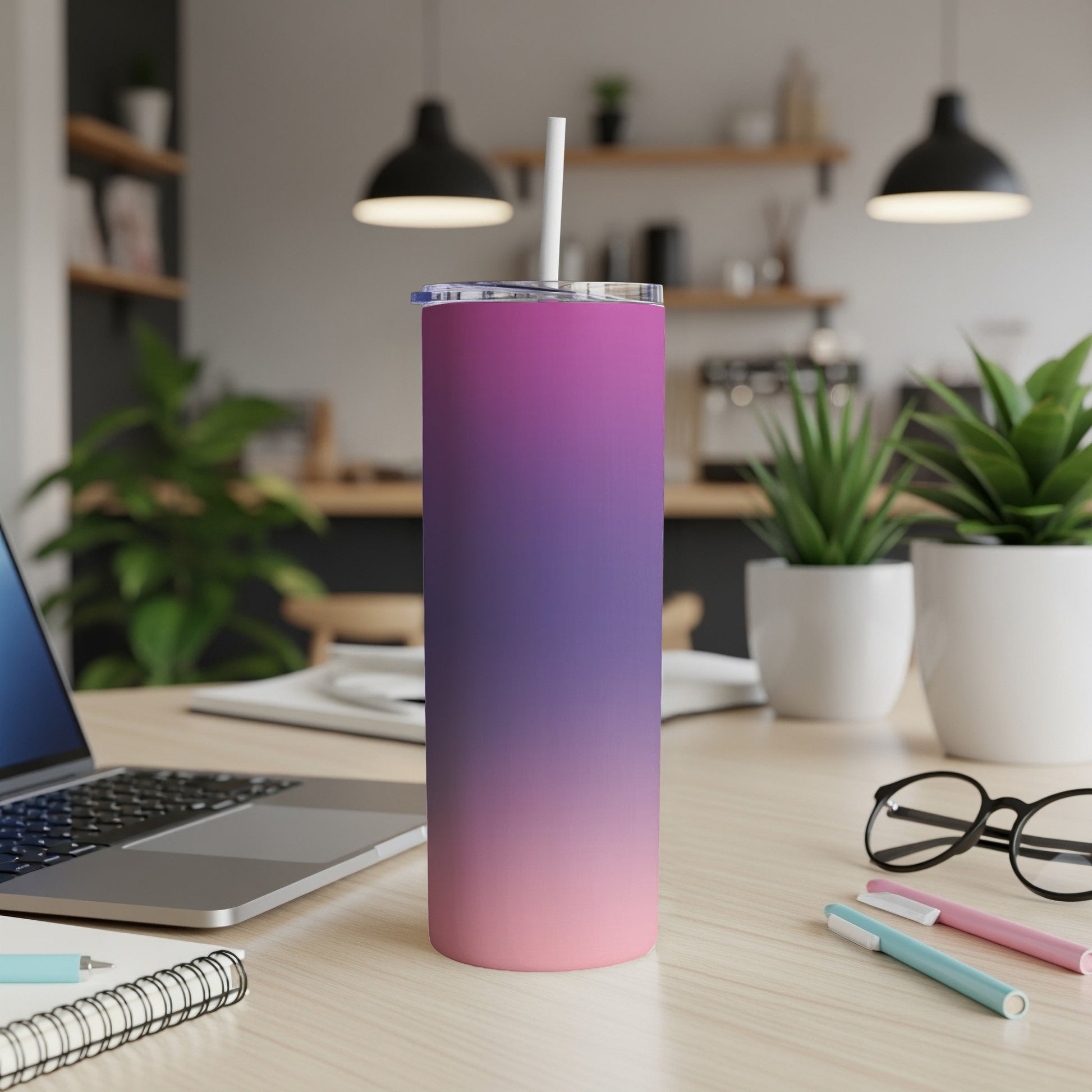 Gradient pink and purple tumbler with straw on desk.