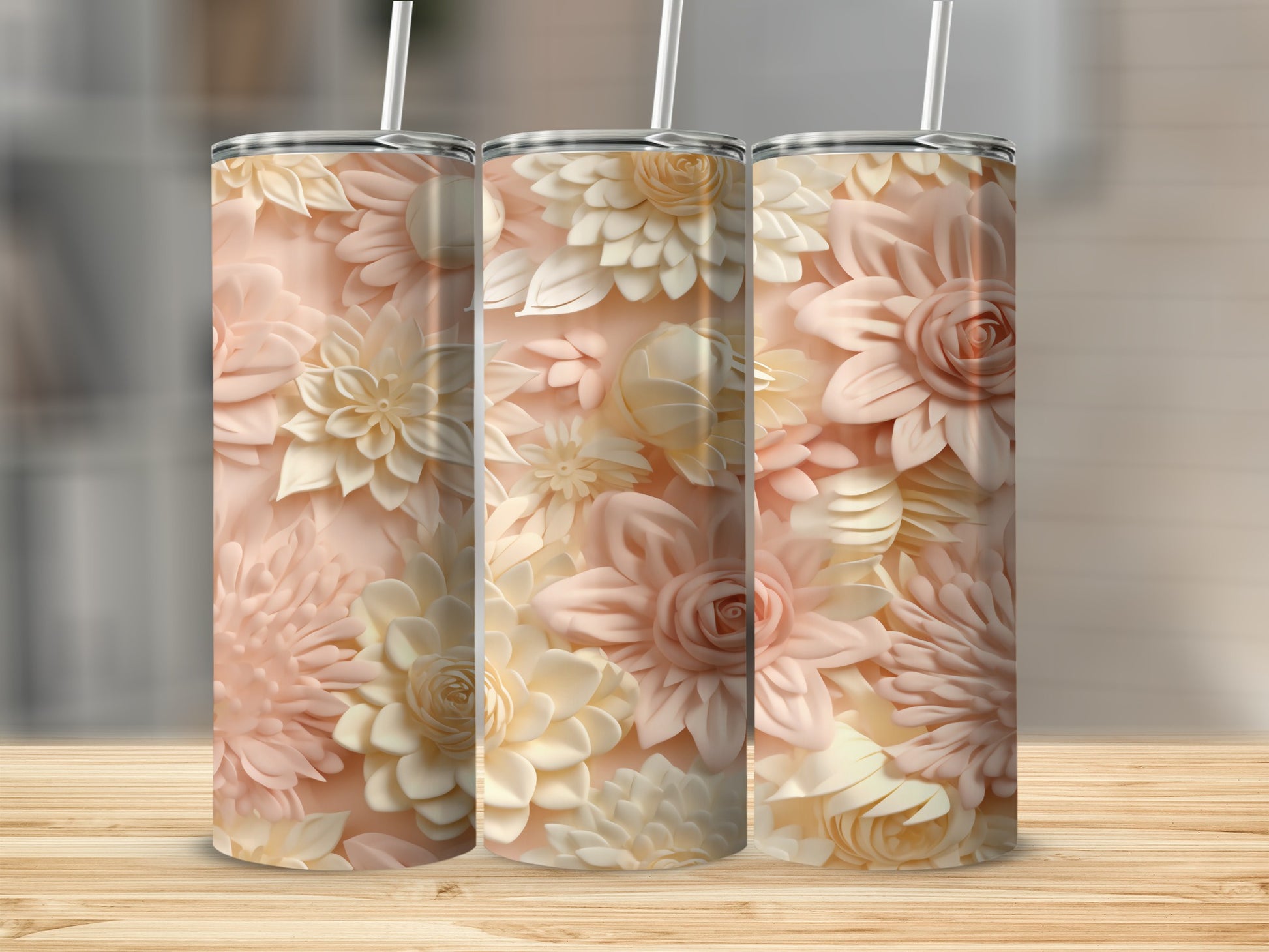 Three pastel floral tumblers with straws on a wooden surface.