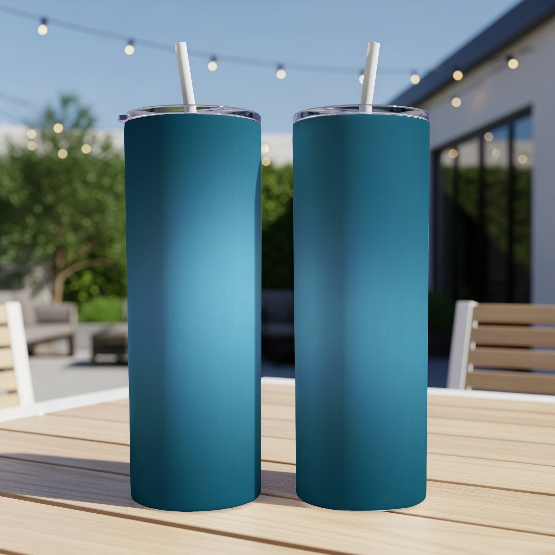 Two teal tumblers with straws on a wooden table.