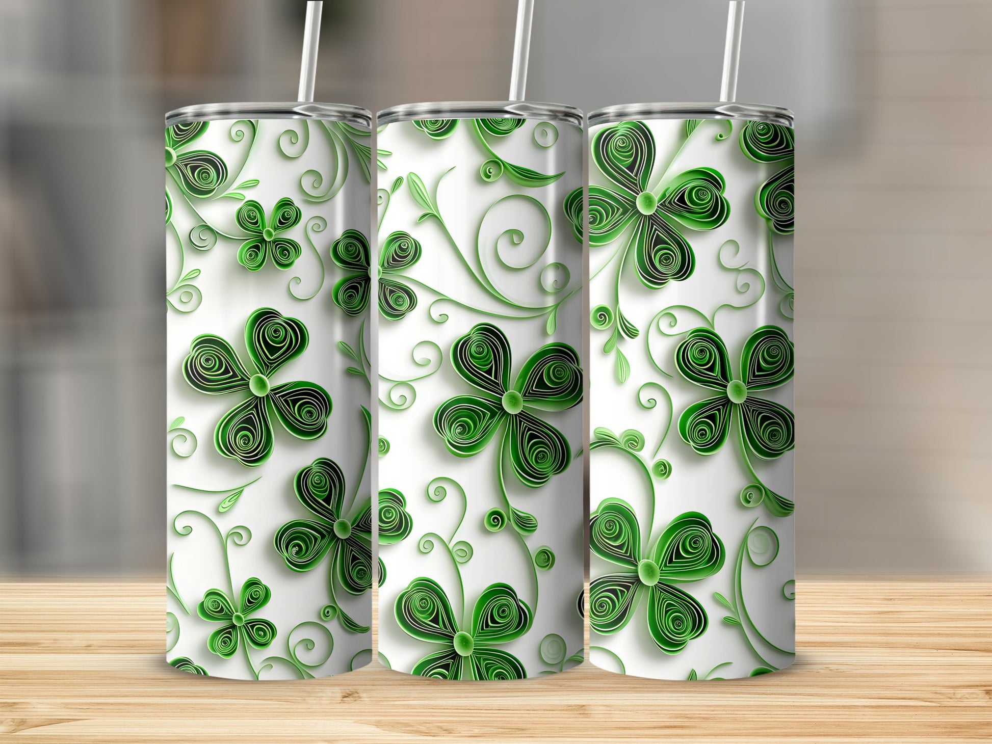 Three tumblers with green clover leaf patterns on a wooden surface.