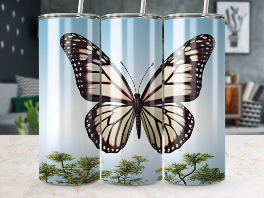 White and black monarch butterfly on a tumbler with greenery.