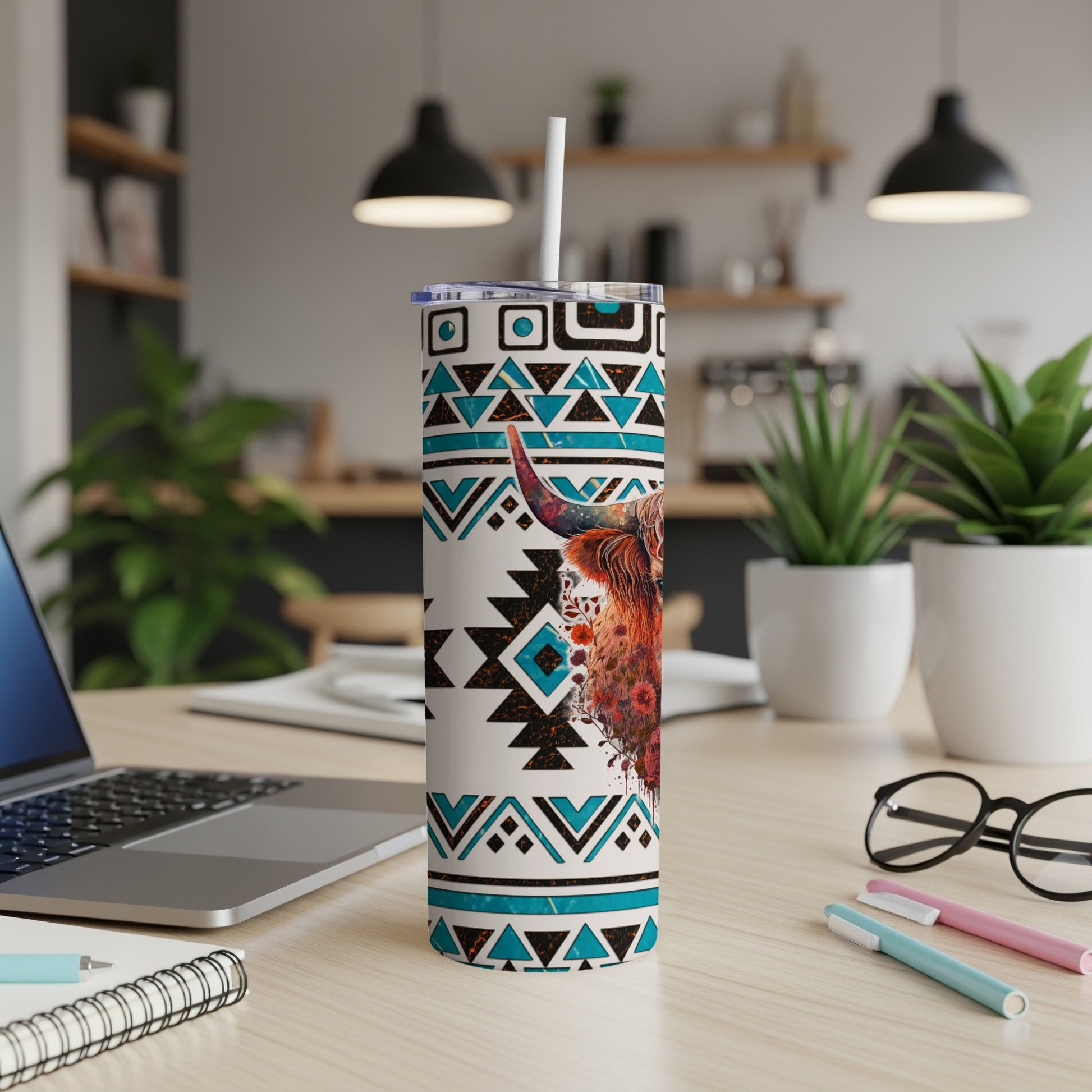 Highland cow tumbler with tribal pattern and straw on a desk.