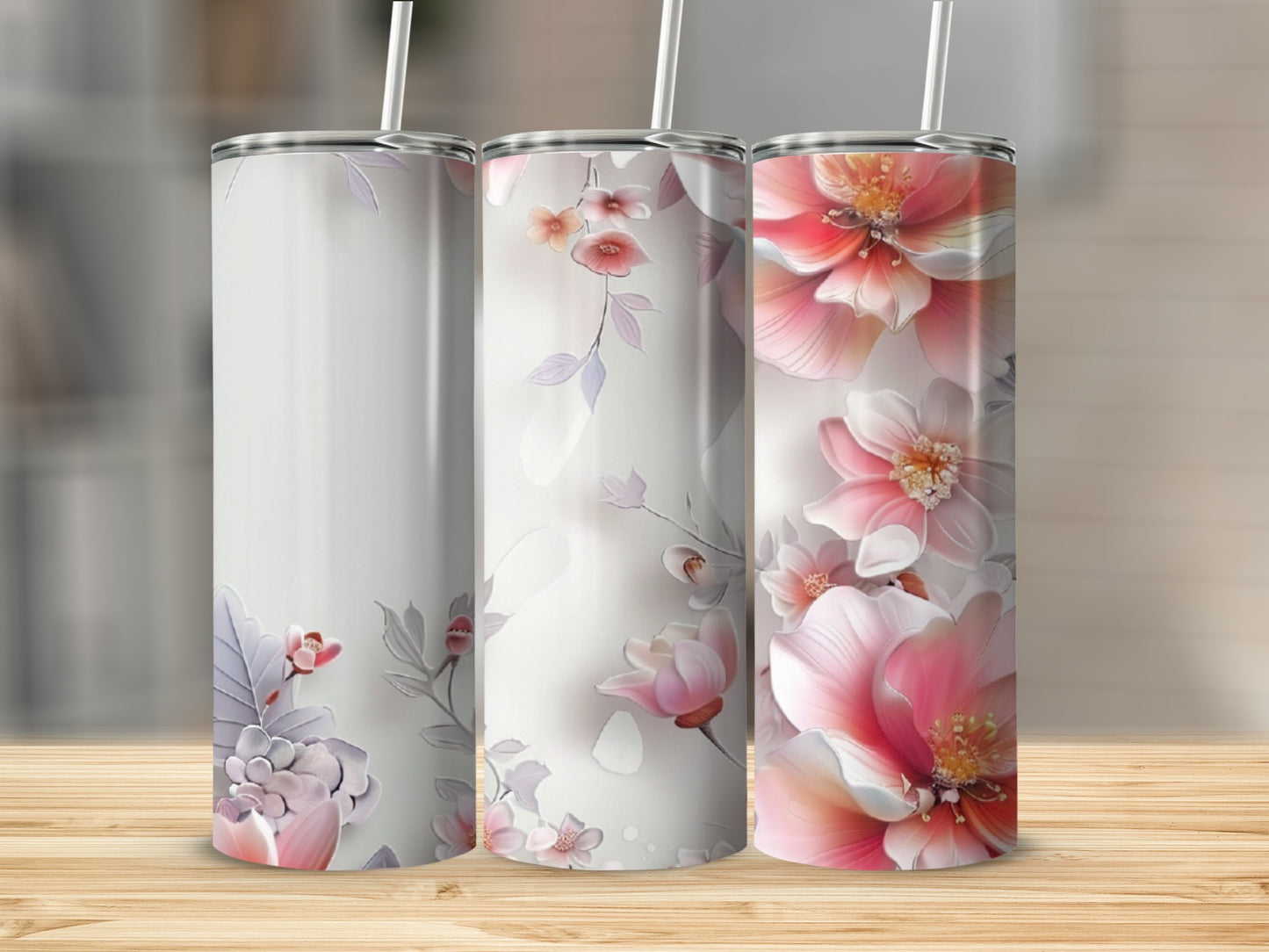Three tumblers with floral designs in shades of pink and purple on a wooden surface.