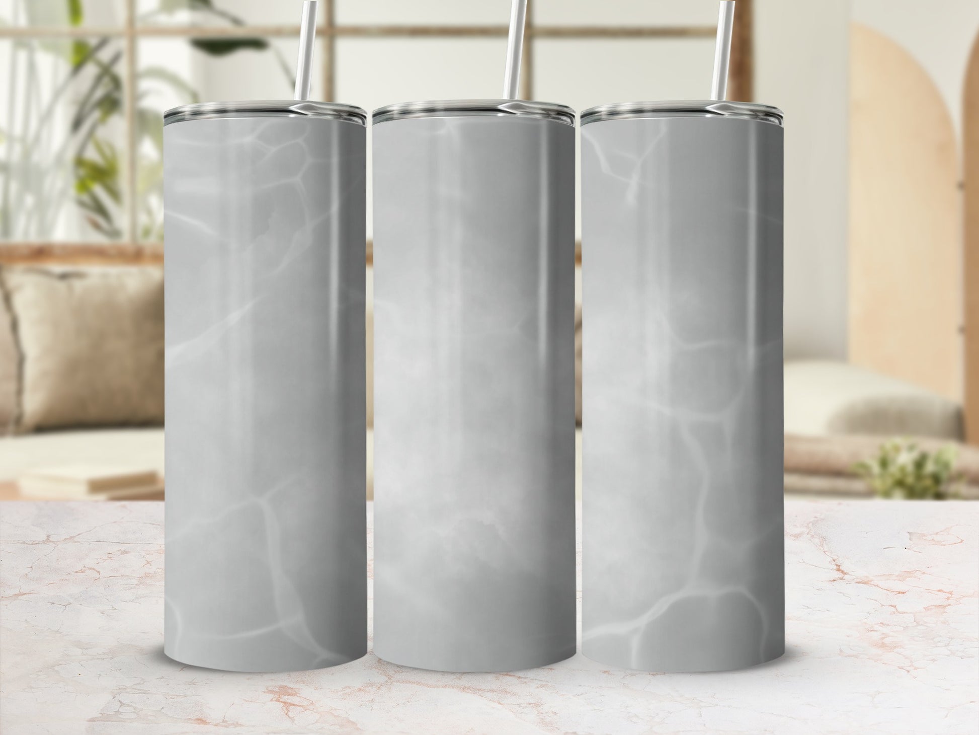 Three stainless steel tumblers with a marble pattern and straws.