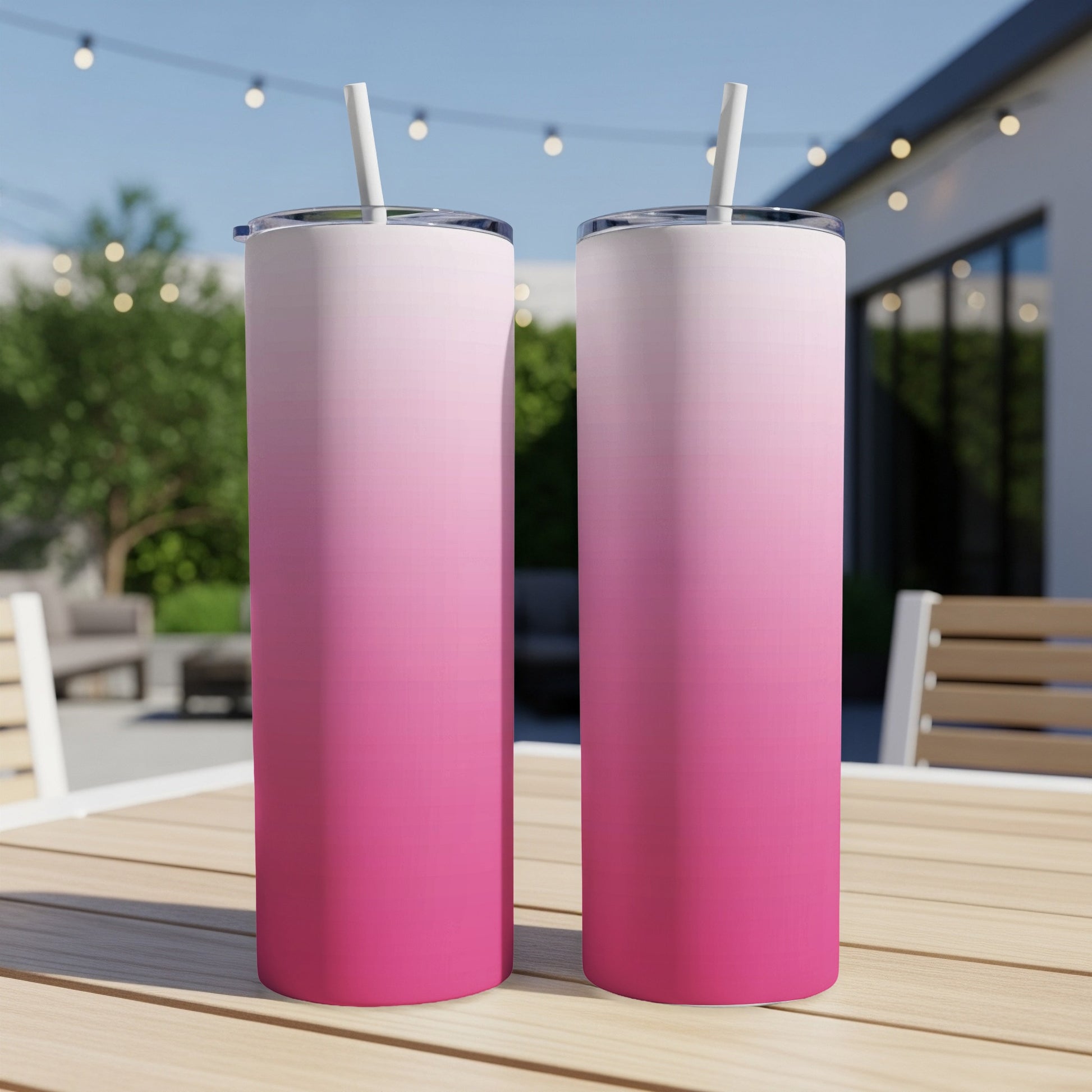 Two pink ombre tumblers with straws on a wooden table.