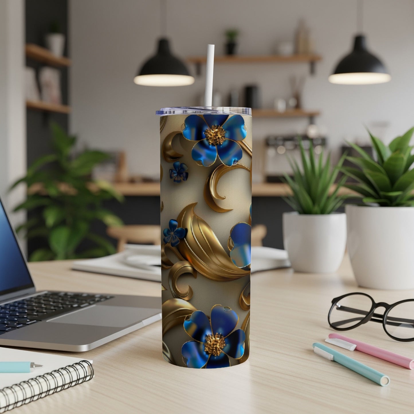 Blue and gold floral pattern on a tall tumbler with straw on a desk.