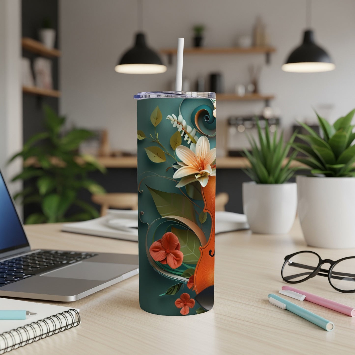 Tumbler with floral violin design and straw on a desk.