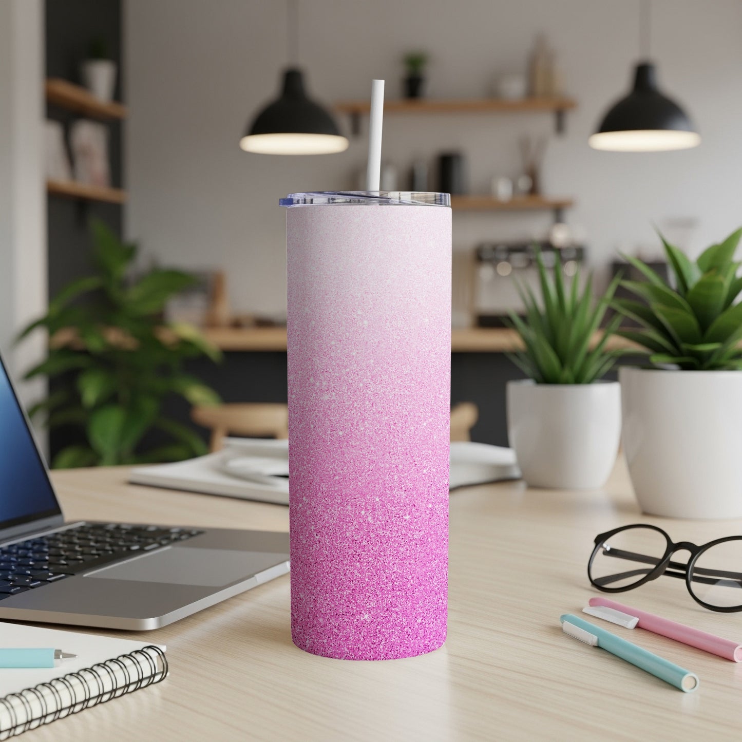 Pink glitter ombre tumbler with white straw on a desk.