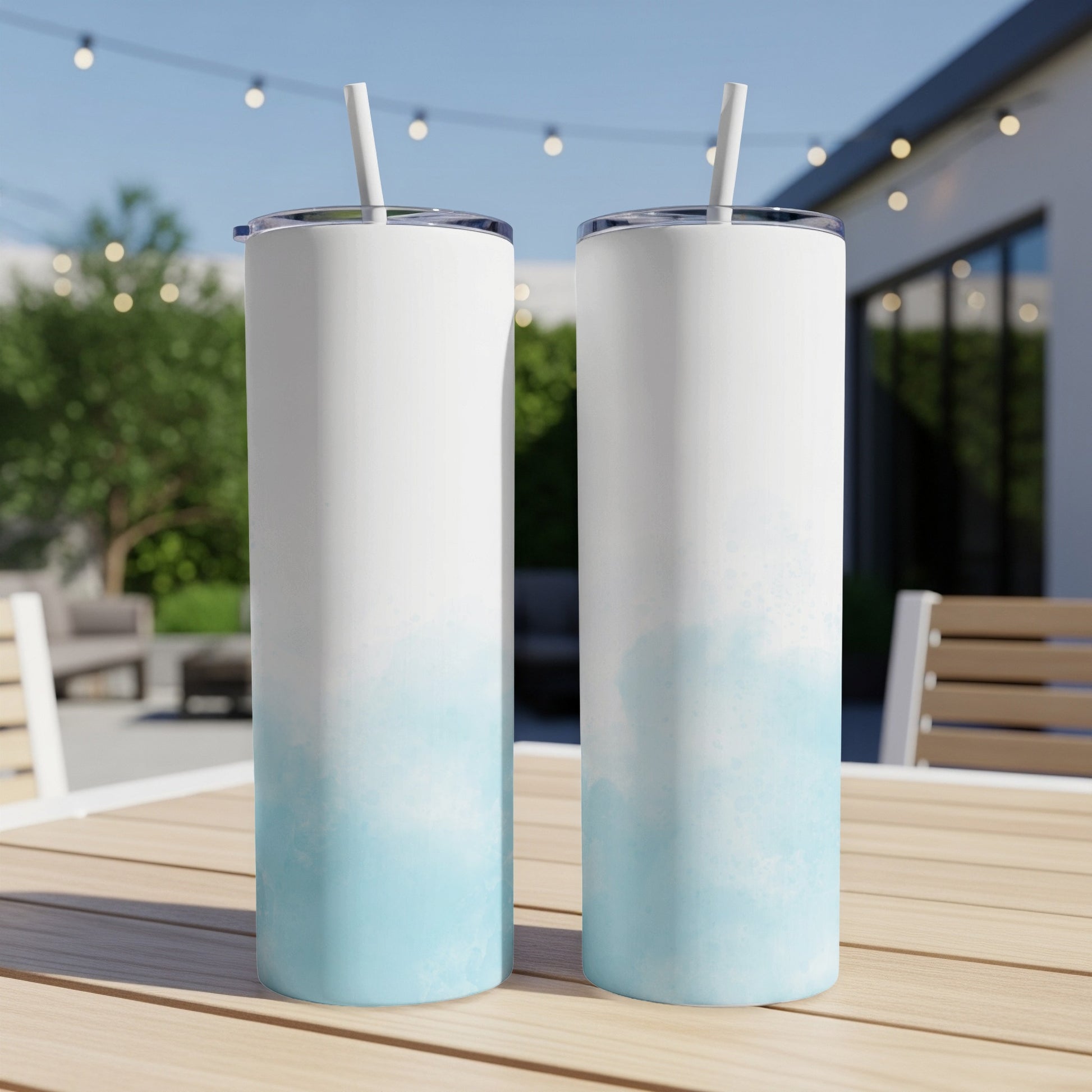 Two white tumblers with blue watercolor splashes on a wooden table.