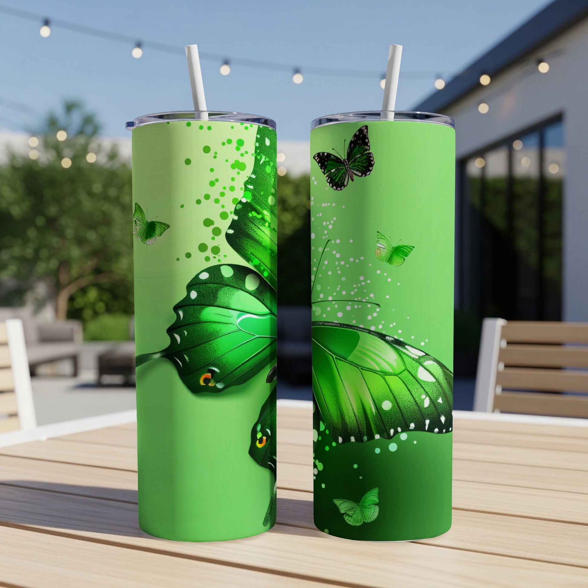 Green tumbler with butterfly design and straw, shown outdoors.