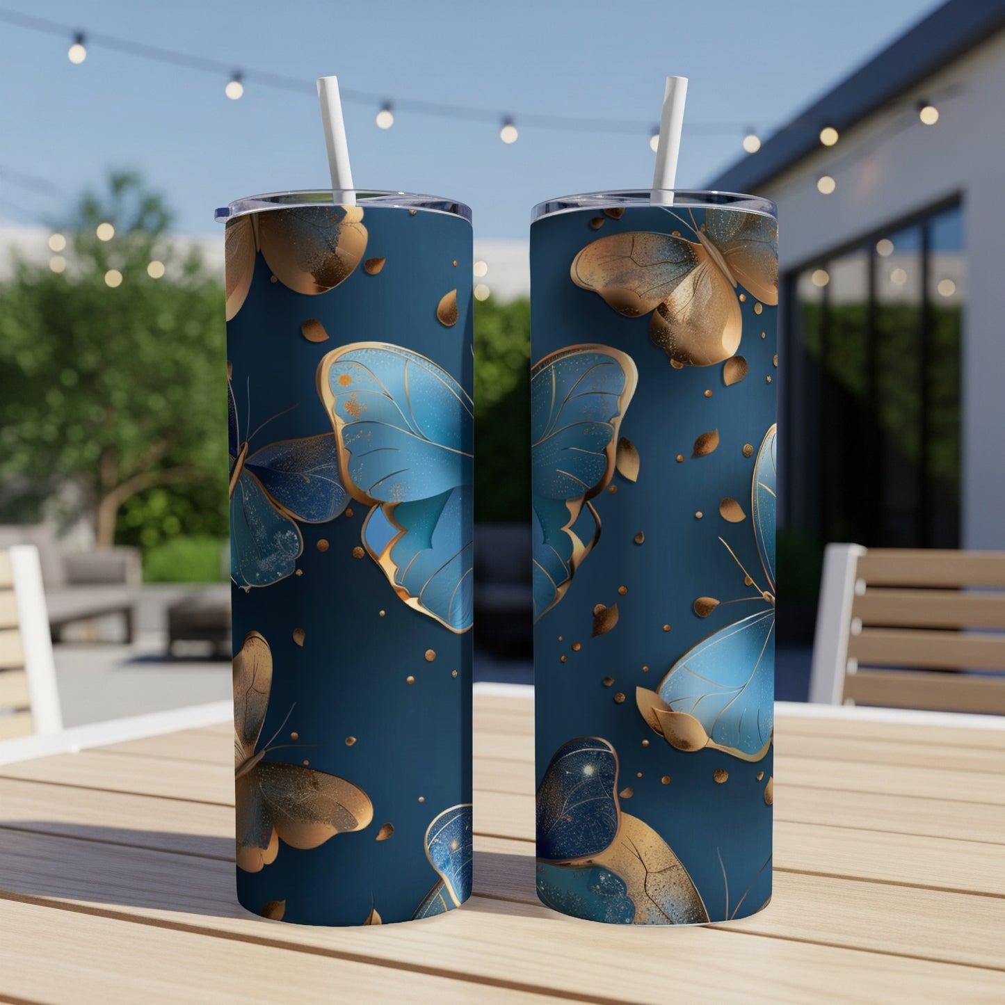 Two navy tumblers with gold and blue butterfly pattern and straws.