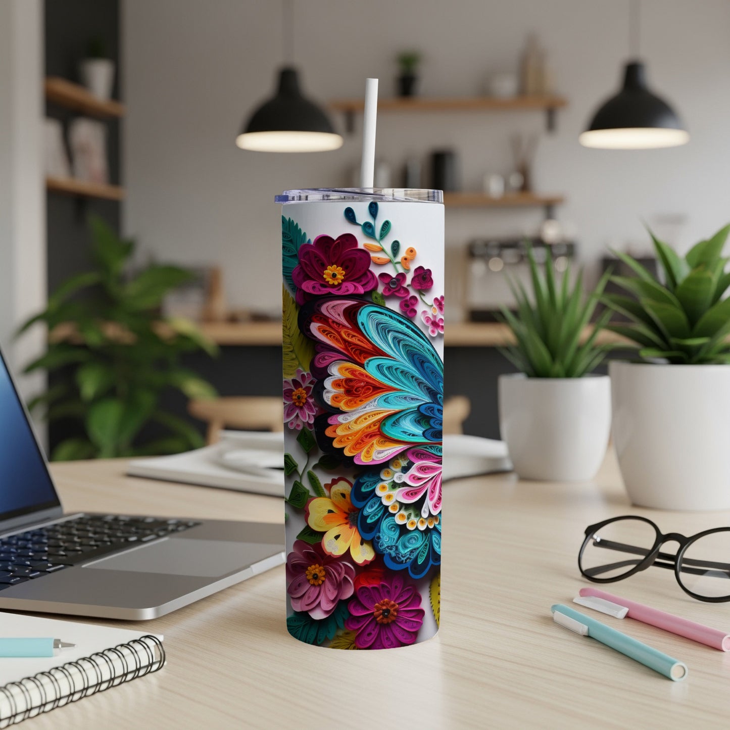 White tumbler with colorful floral and butterfly design on desk.