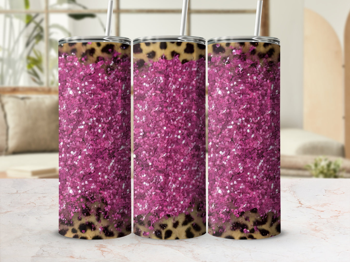 Three pink glitter tumblers with leopard print detail stand on a marbled surface.