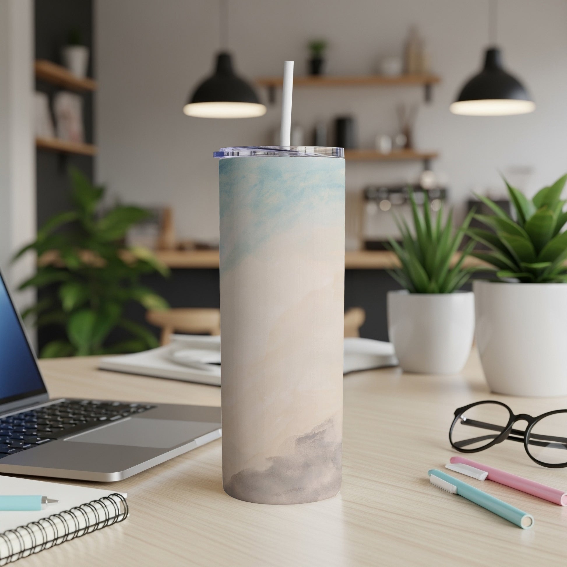 Tall tumbler with abstract blue and beige watercolor design and straw.