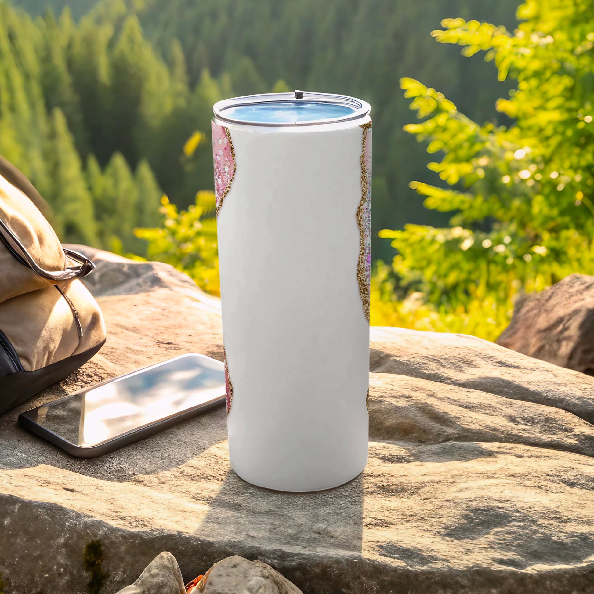 White tumbler with glittery pink and gold pattern on a rock.