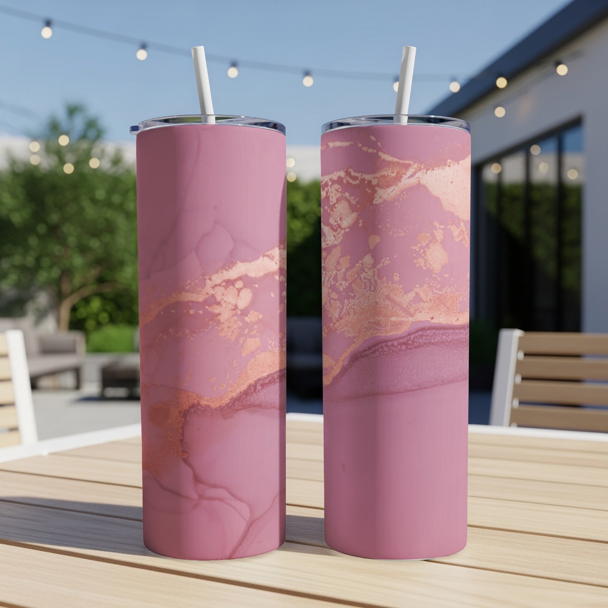 Two pink tumblers with marble and rose gold accents on a wooden table.