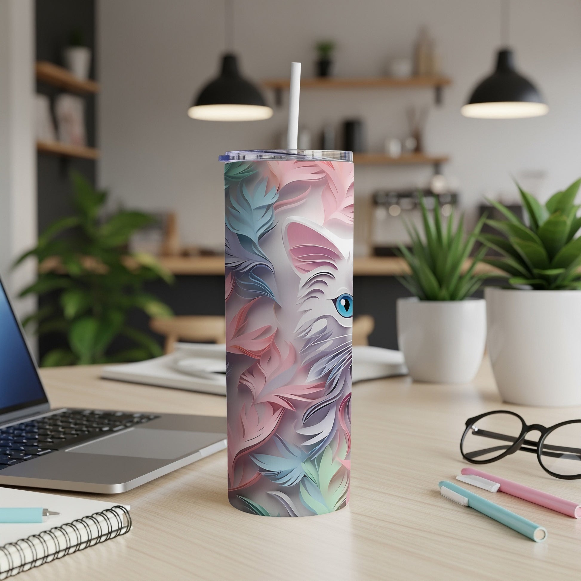 White cat face design on a pink and blue feather patterned skinny tumbler.