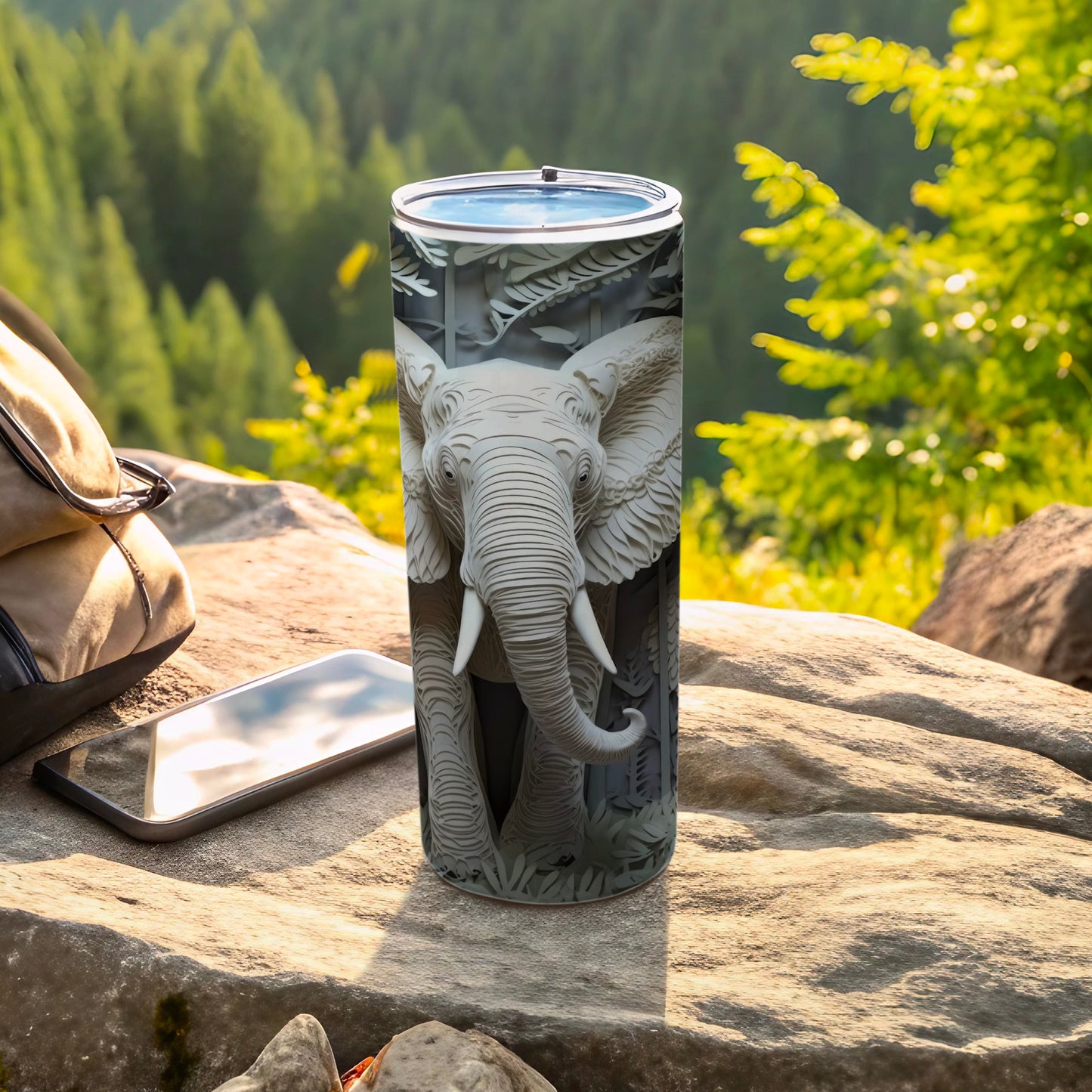 Gray tumbler with embossed elephant head design, resting on rocks.