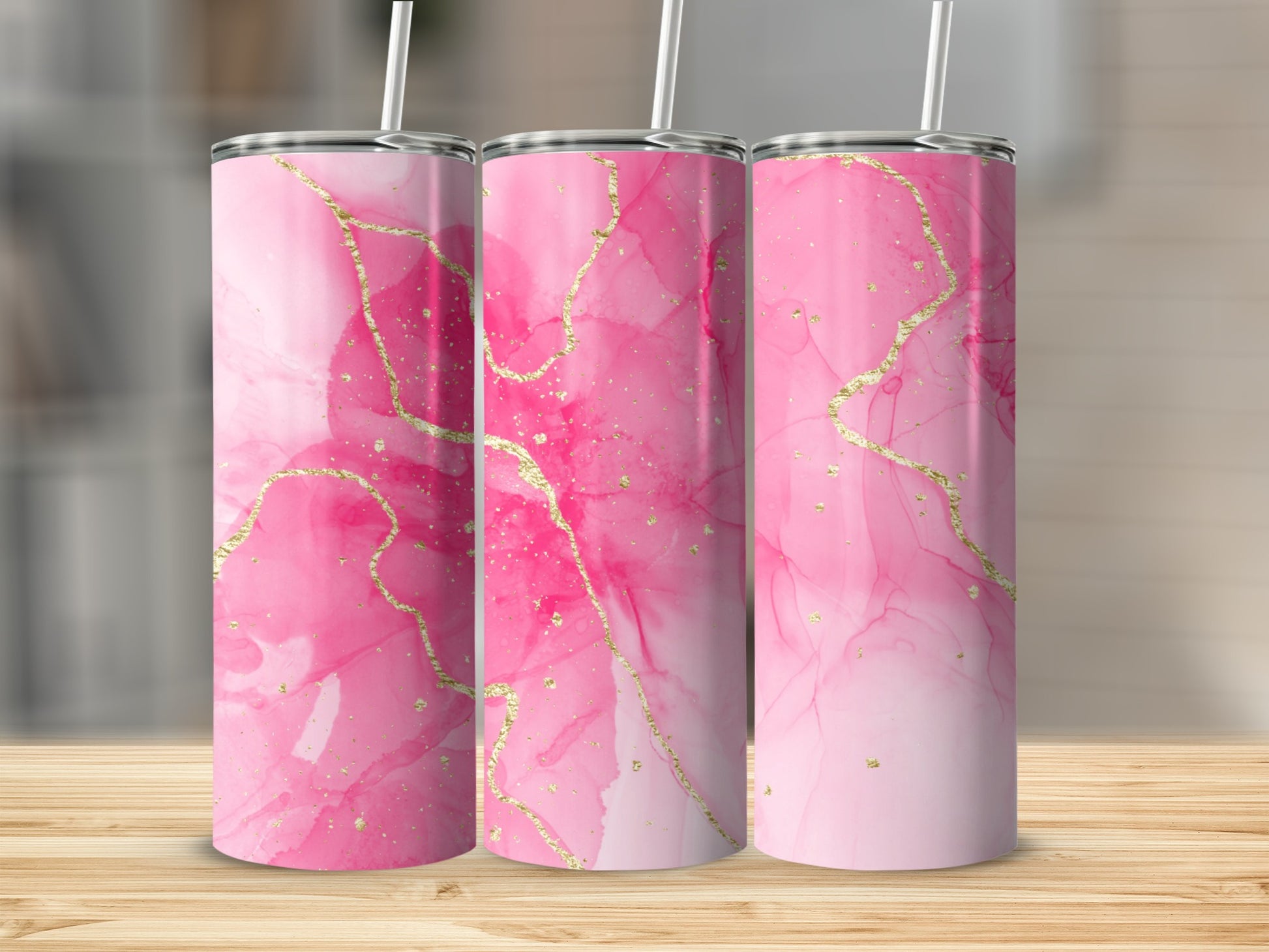 Pink watercolor tumbler with gold accents, on a wooden surface.