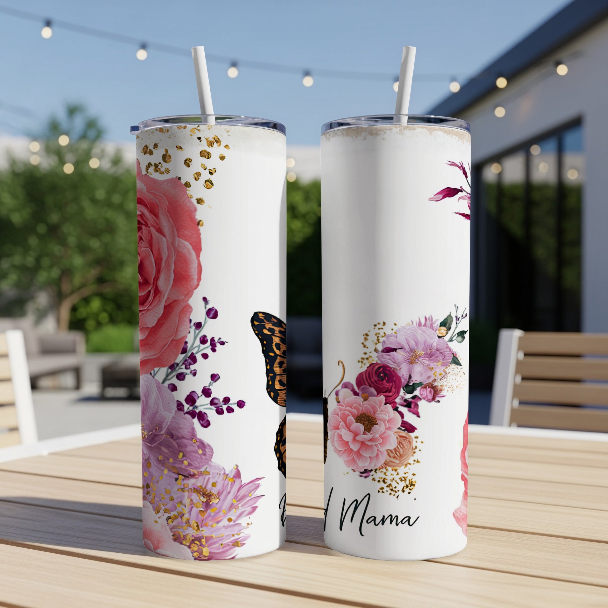Two white tumblers with floral and butterfly designs, one reading "Proud Mama".