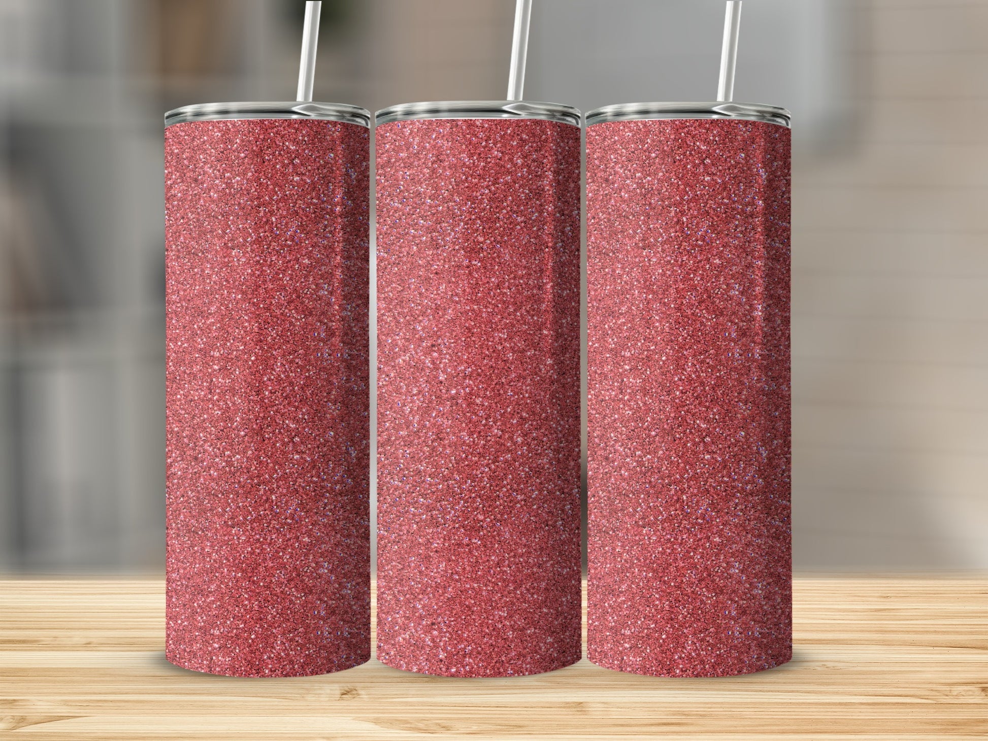 Three rose gold glitter tumblers with straws stand on a wooden surface.