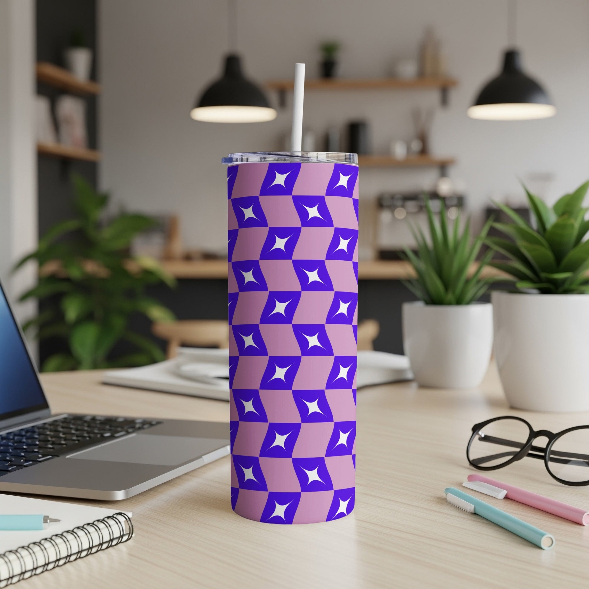 Purple and blue geometric pattern tumbler with straw on desk.