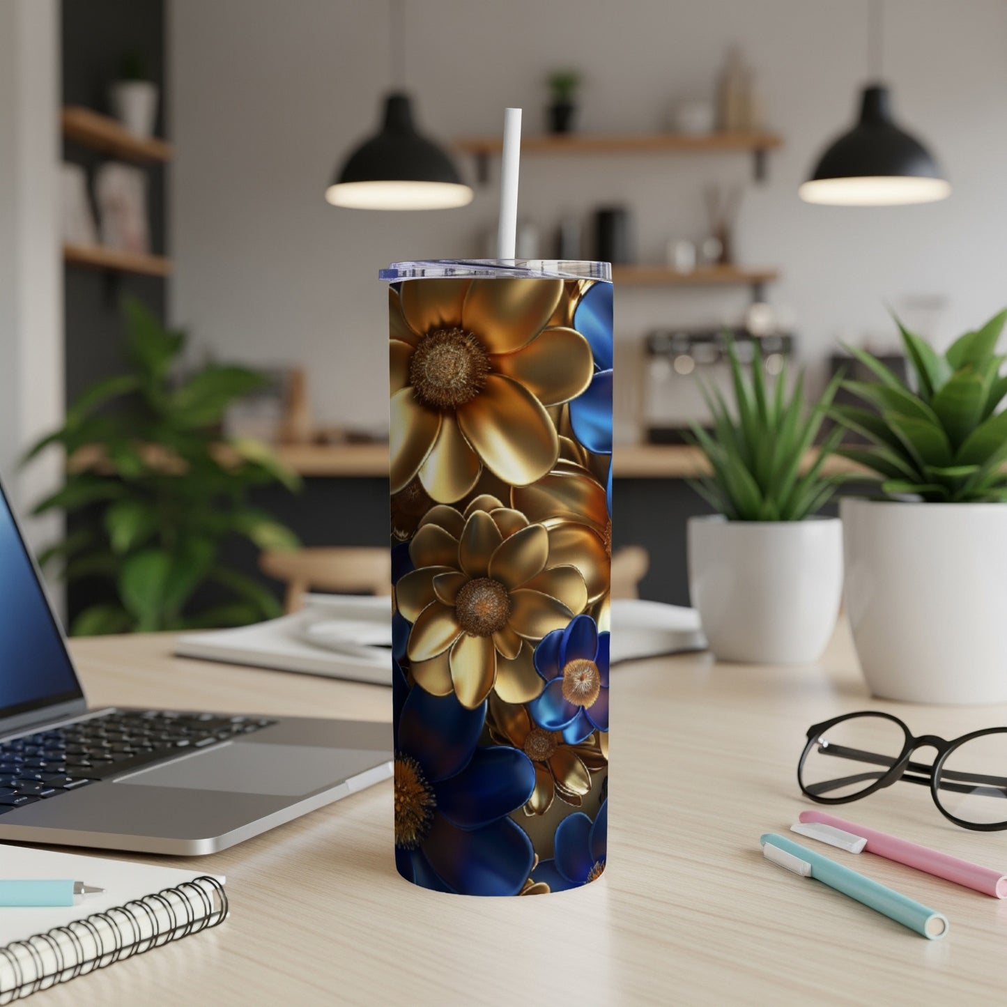 Blue and gold floral print tumbler with straw on a desk.