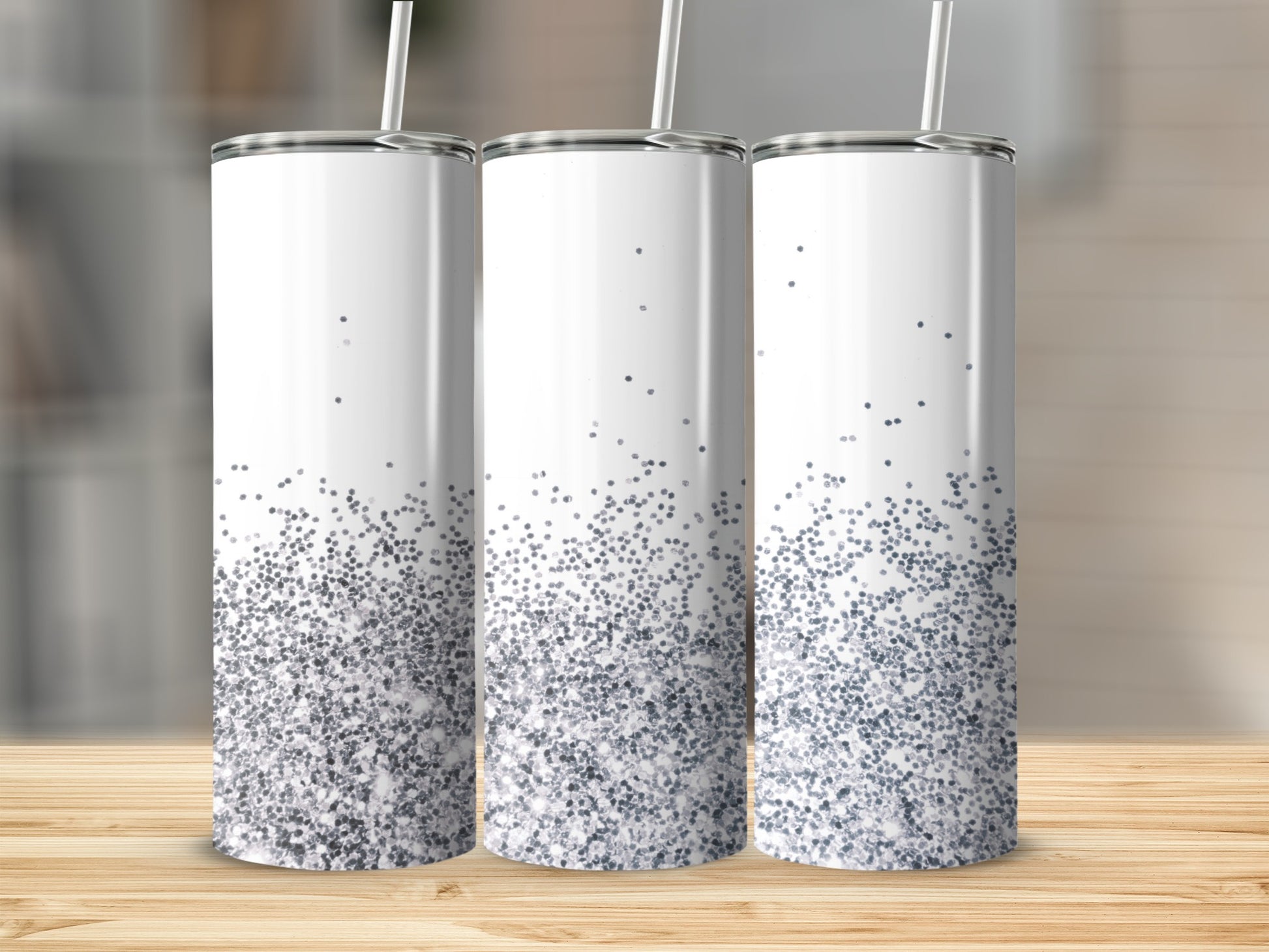 Three white tumblers with silver glitter at the bottom on a wooden surface.