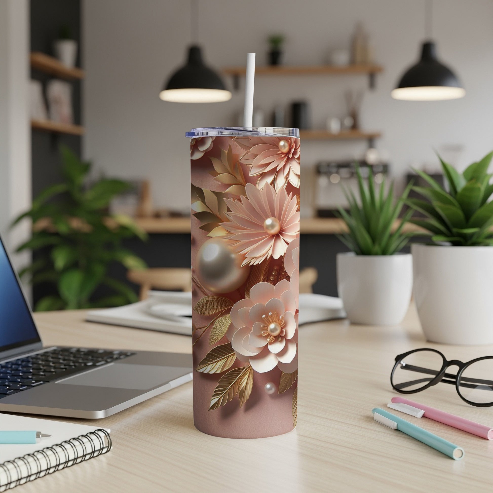Rose gold floral pattern tumbler with pearls and straw on desk.