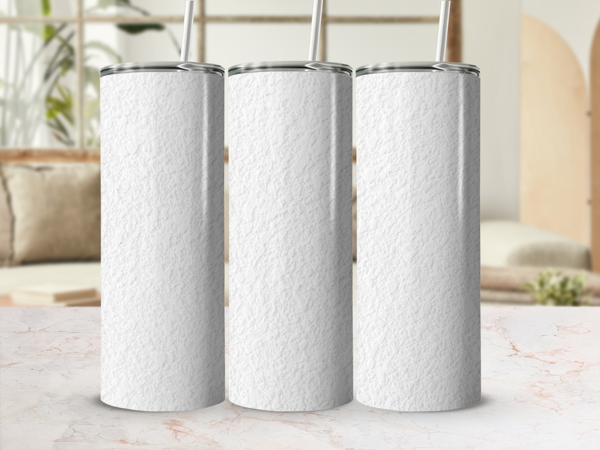 Three white textured tumblers with straws on a marble surface.