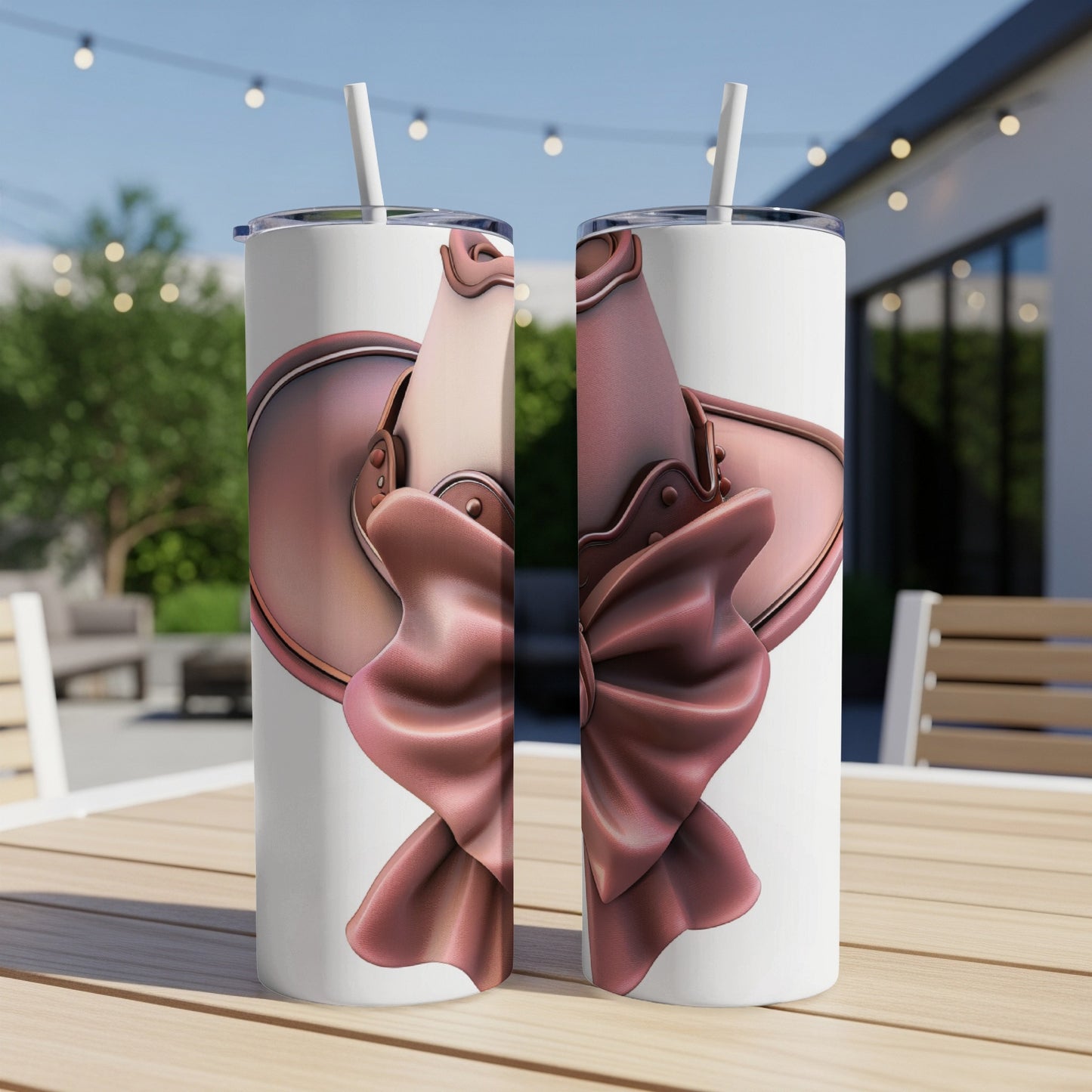 Two tumblers with a pink bow design sit on a table outdoors.