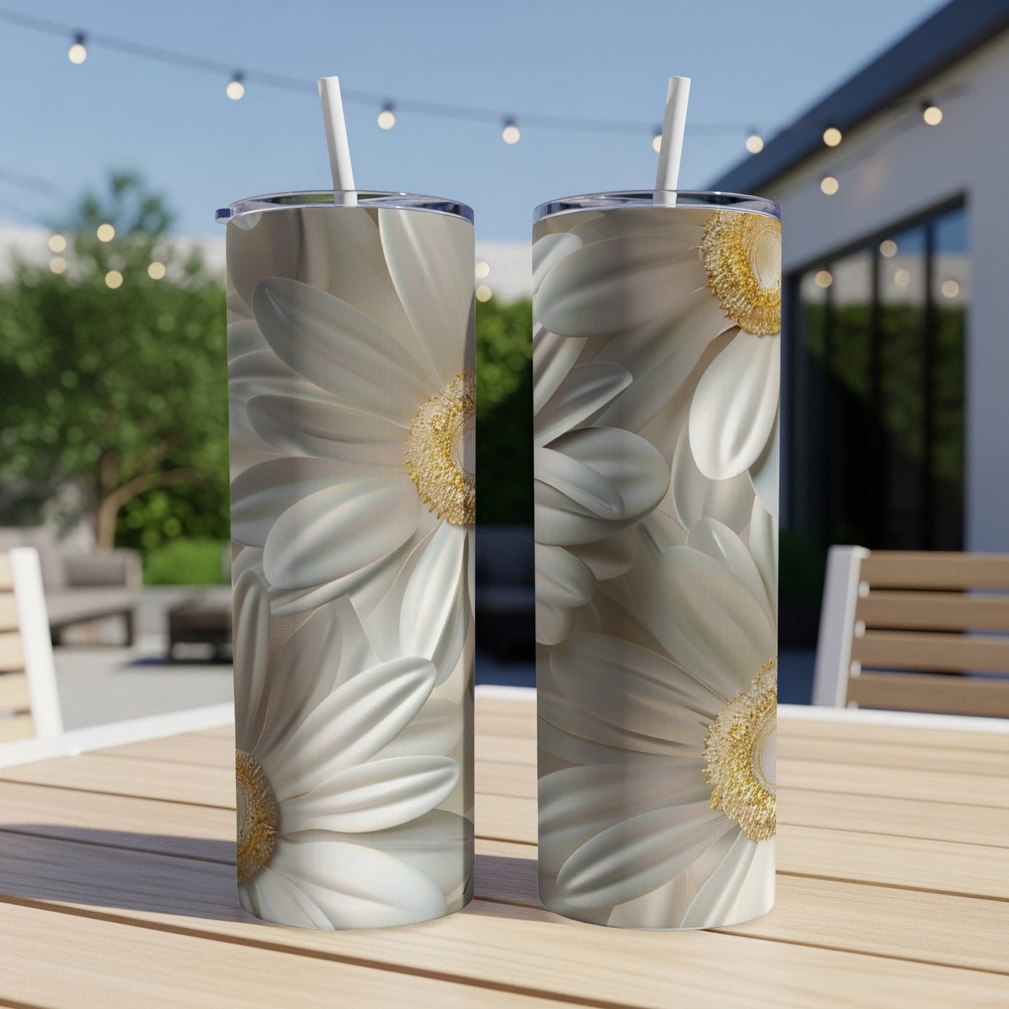Two white daisy tumblers with straws on a wooden table outdoors.