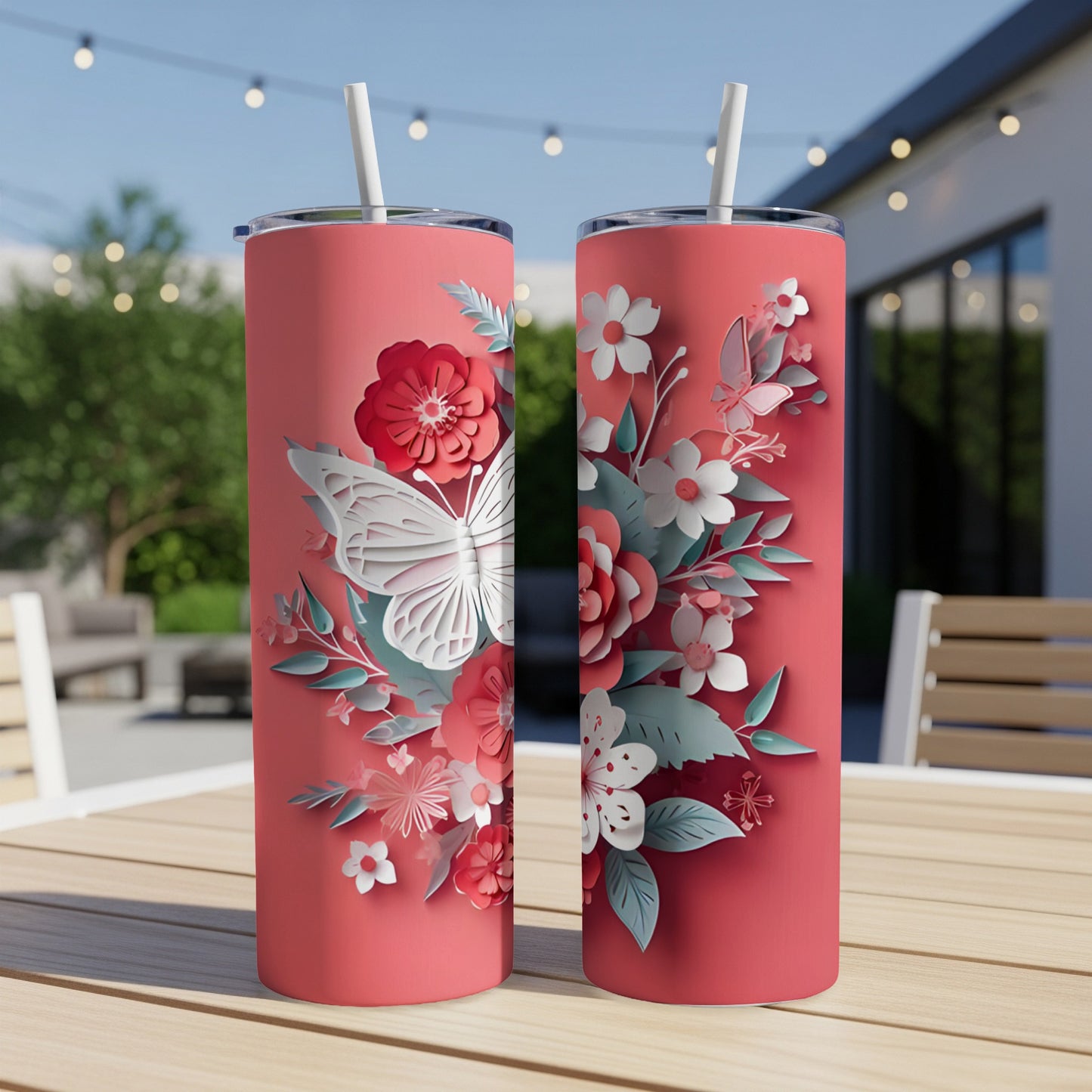Two pink tumblers with white butterfly and floral paper cutouts on a table.