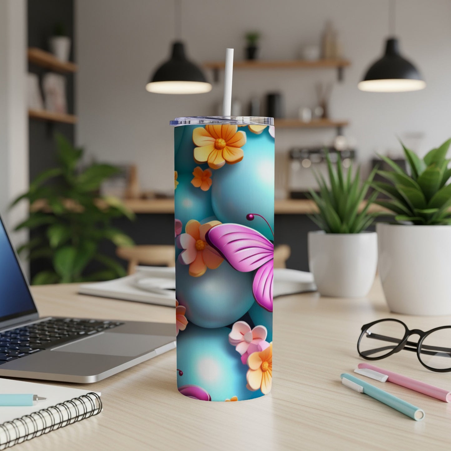 Teal tumbler with pink butterfly and floral accents on a desk.