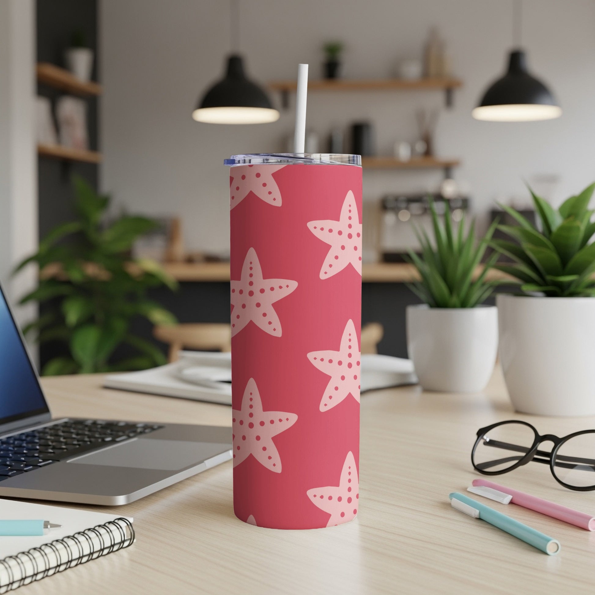 Red tumbler with a white starfish pattern, on a wooden desk.