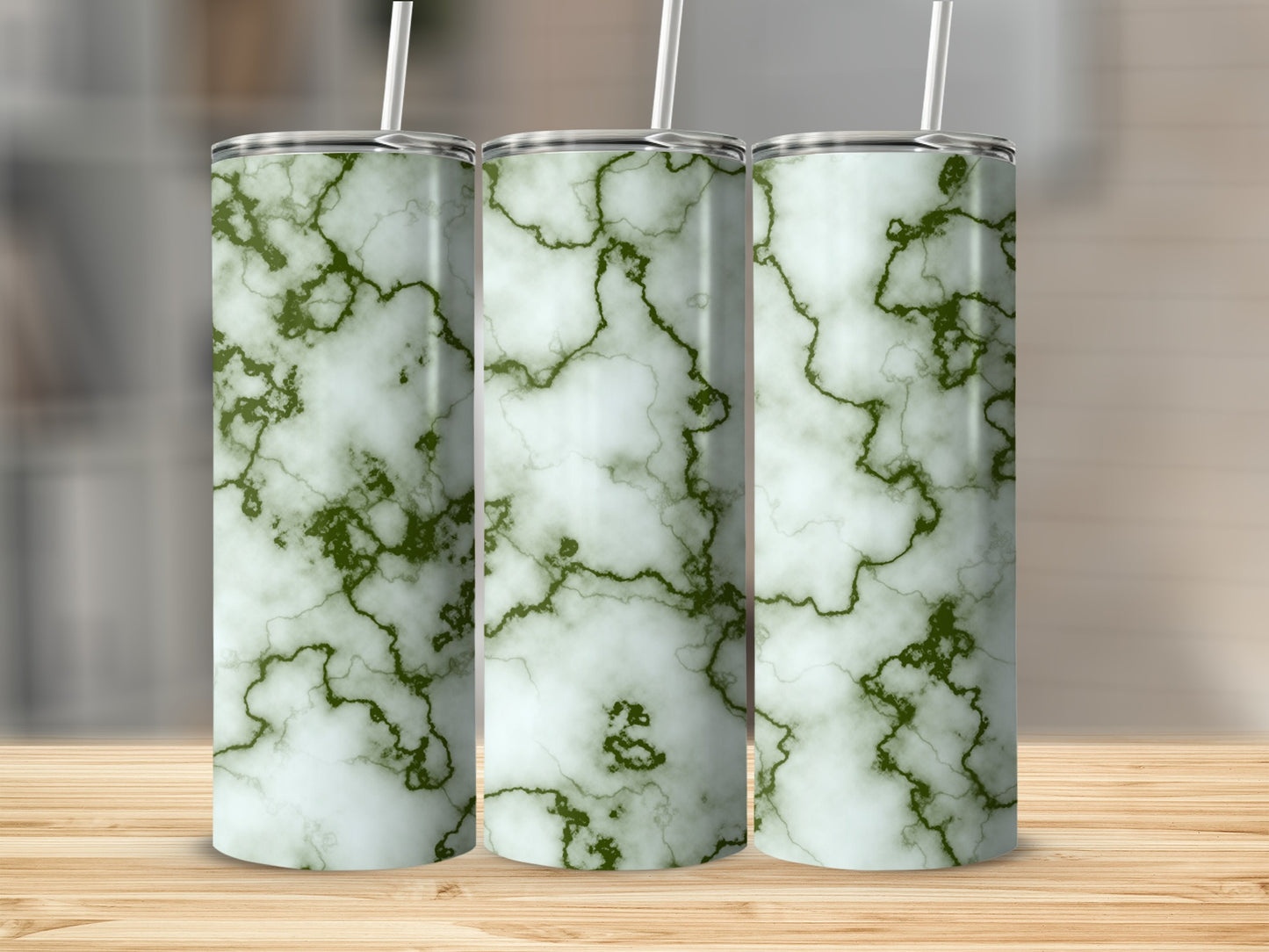 Three green and white marbled tumblers with straws on a wooden surface.