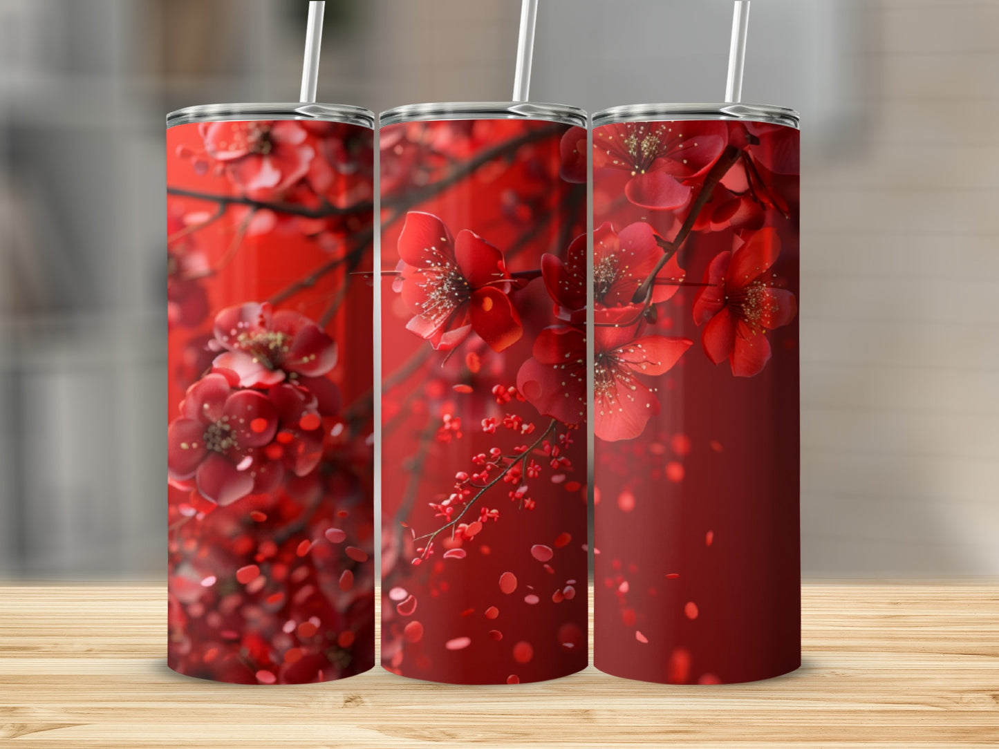 Three red floral tumblers with white straws, set against a blurred background.