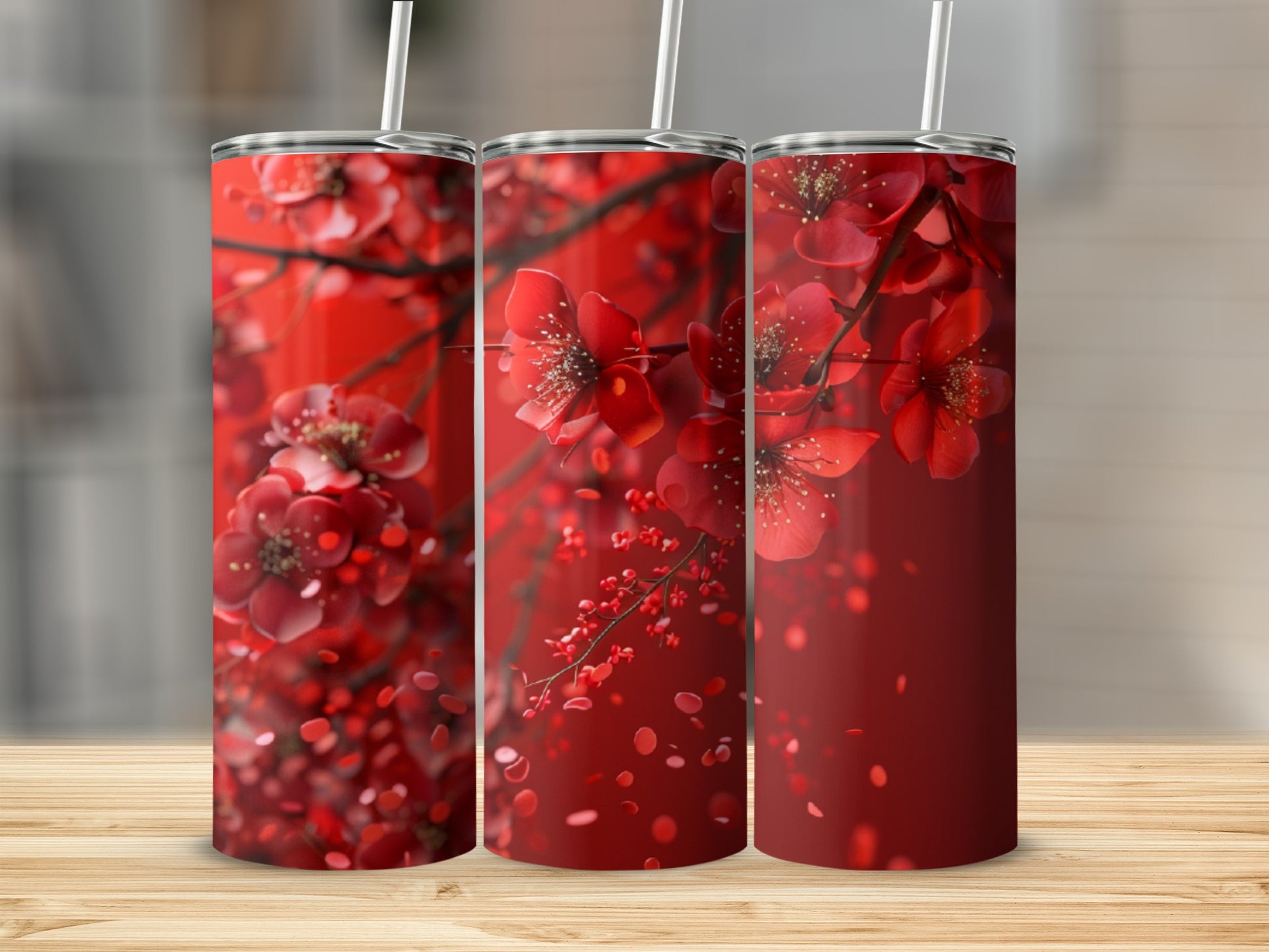Three red floral tumblers with white straws, set against a blurred background.