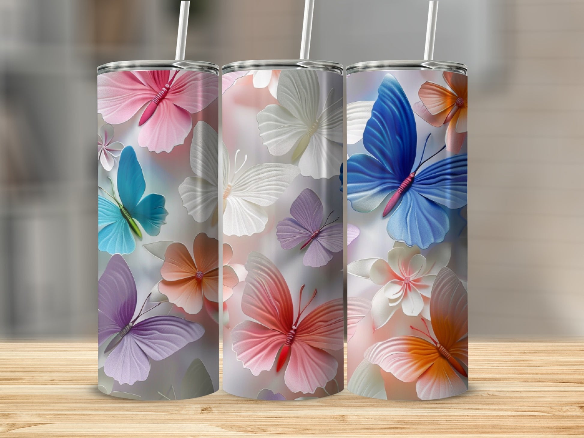 Three tumblers with colorful butterfly and floral designs.