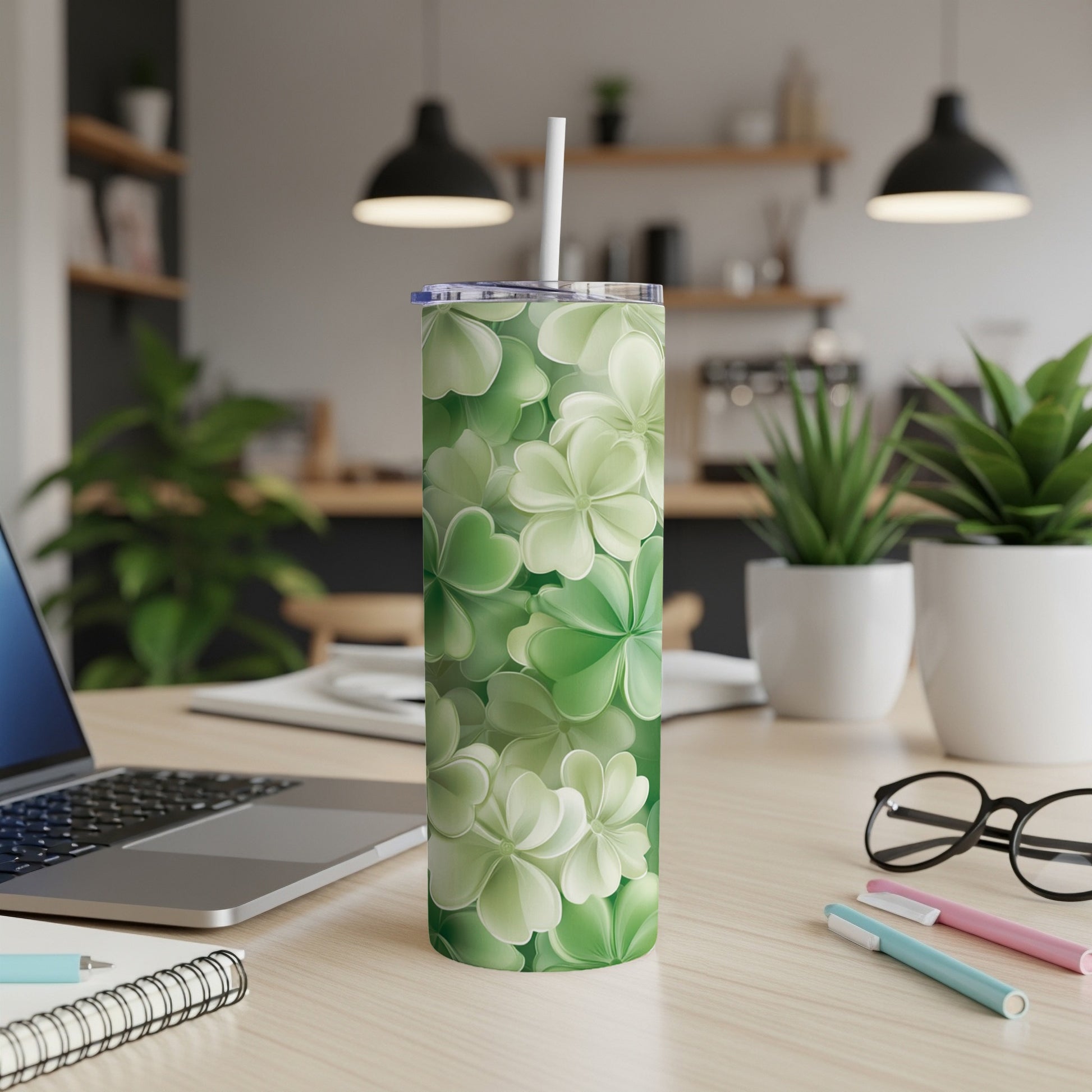 Green clover pattern tumbler with straw on a desk.